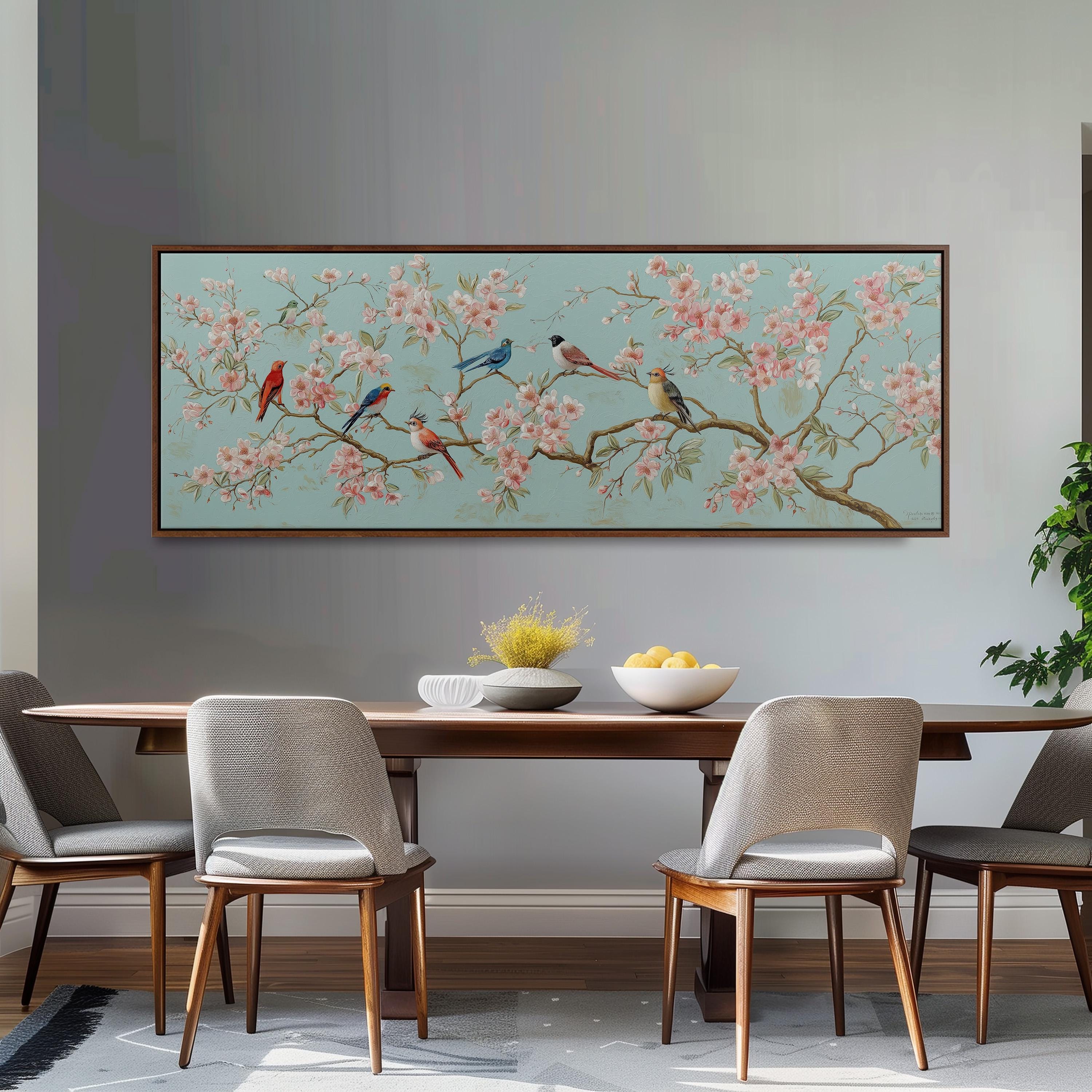 a dining room with a large floral painting hanging on the wall above a wooden table with four chairs. The table is set with a bowl of fruit and a vase of flowers, creating a cozy and inviting atmosphere.