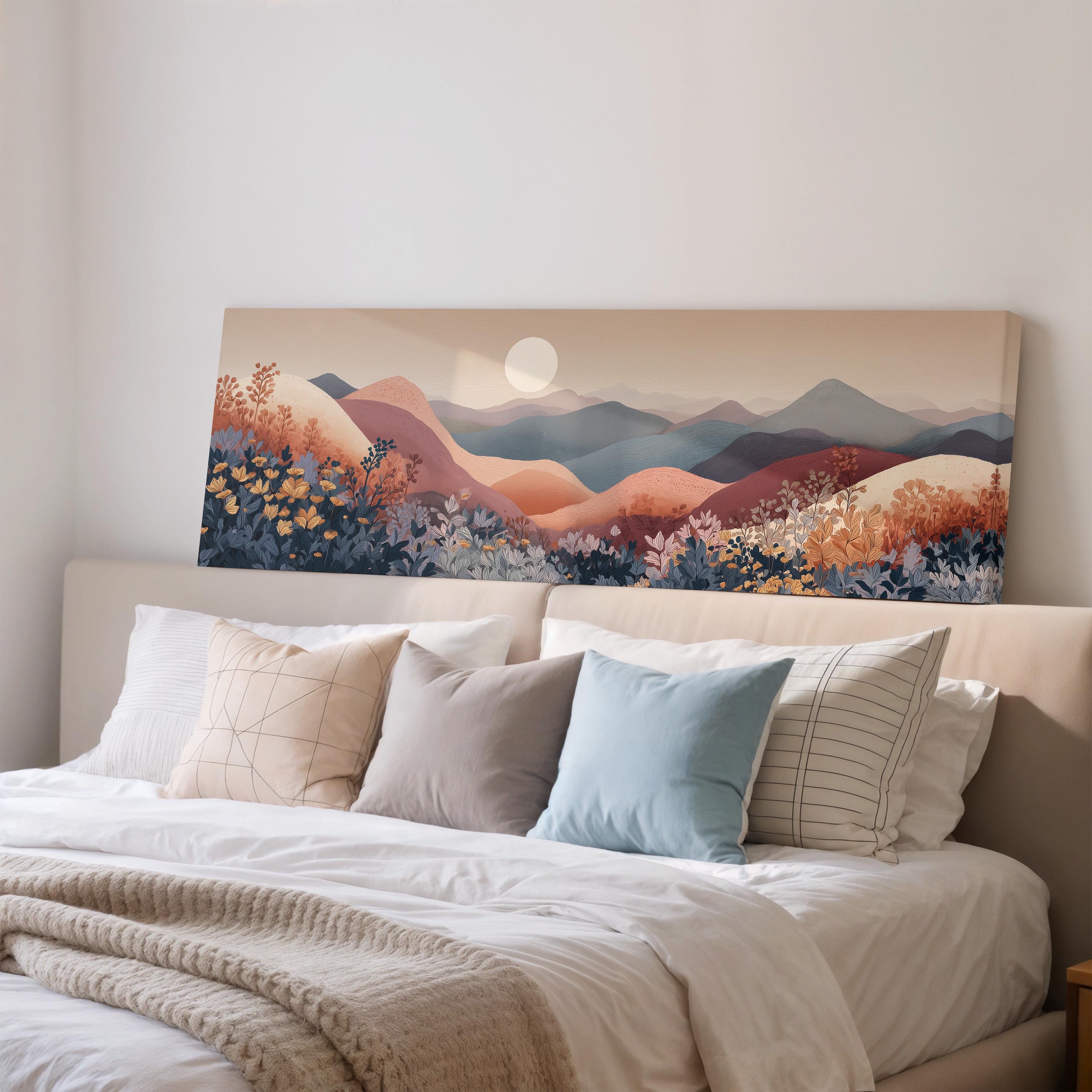 a large, colorful landscape painting hanging on a wall above a bed with white pillows and a gray blanket.