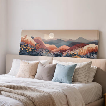 a large, colorful landscape painting hanging on a wall above a bed with white pillows and a gray blanket.