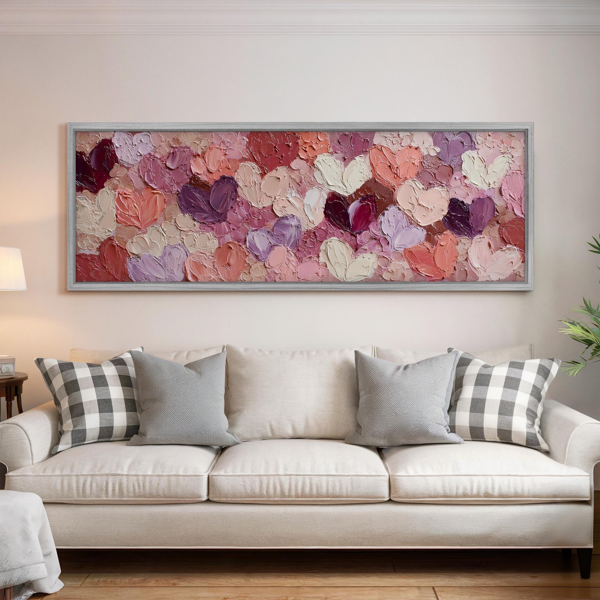 a large, colorful painting of hearts hanging on a wall above a white couch with gray and white pillows.