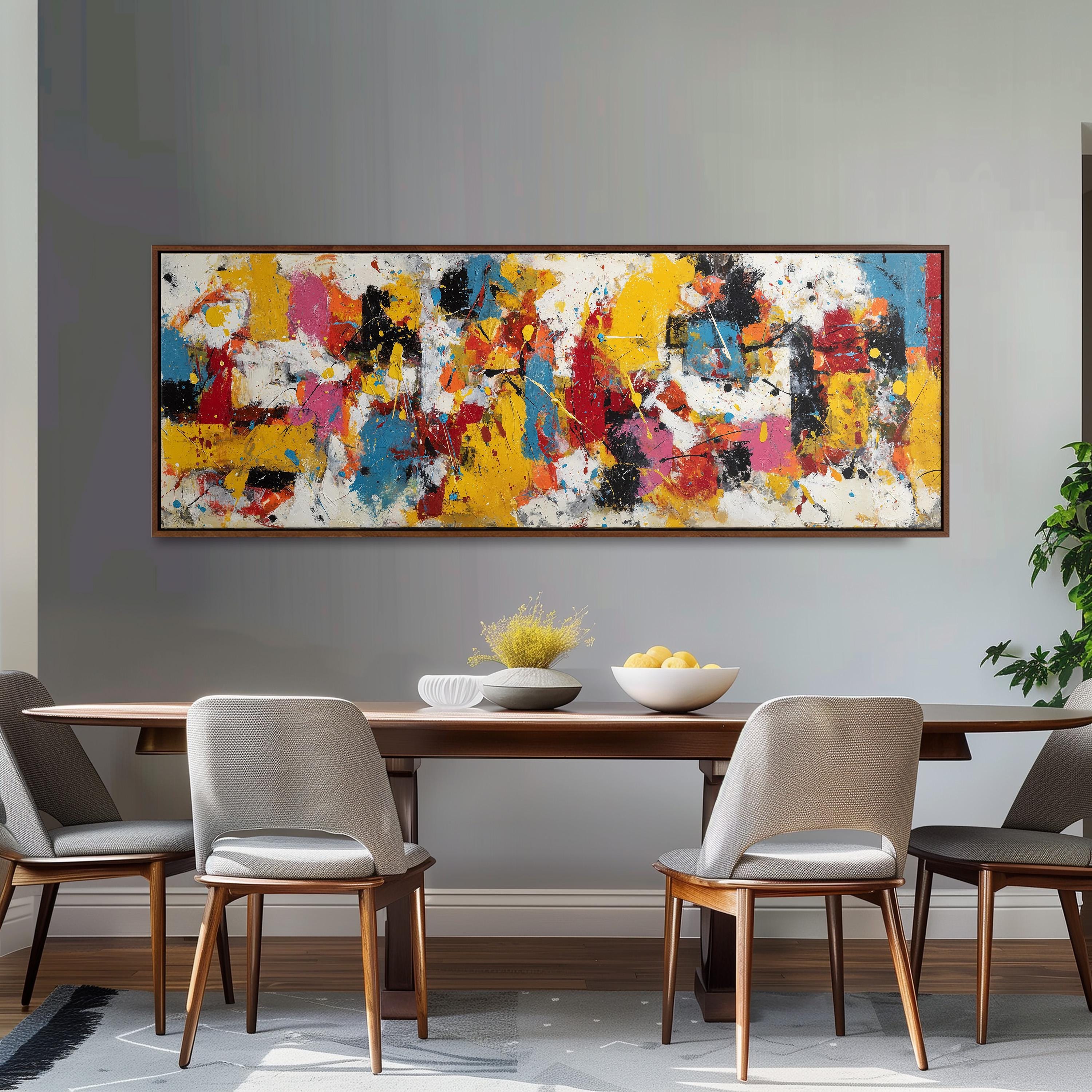a dining room with a large, colorful abstract painting hanging on the wall above a wooden dining table. The table is set with a bowl of fruit and a vase of flowers, creating a welcoming and vibrant atmosphere. The room is furnished with four chairs, two on each side of the table, and a potted plant is visible in the background.