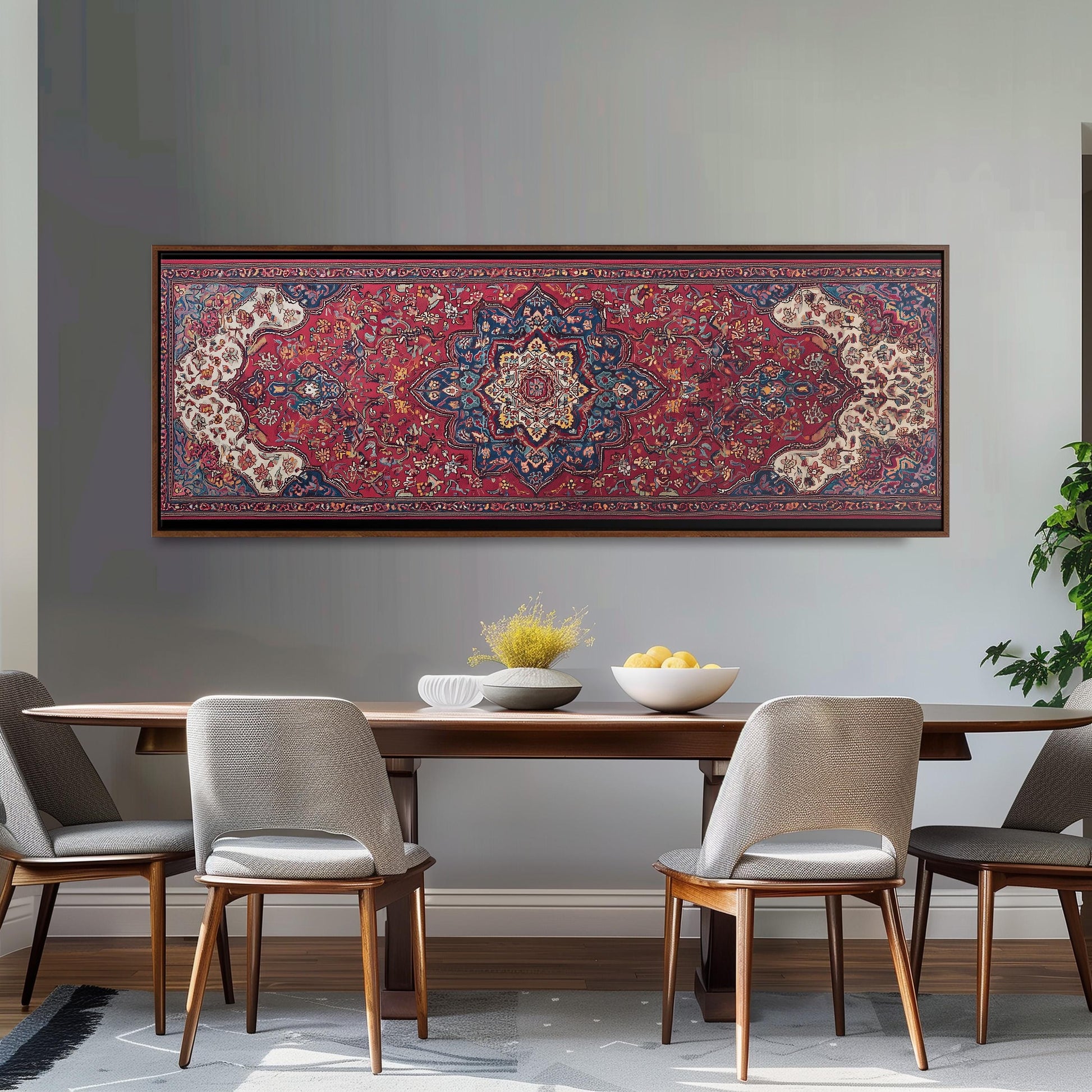a dining room with a wooden table and four chairs, a large framed rug hanging on the wall above the table, and a bowl of fruit on the table.
