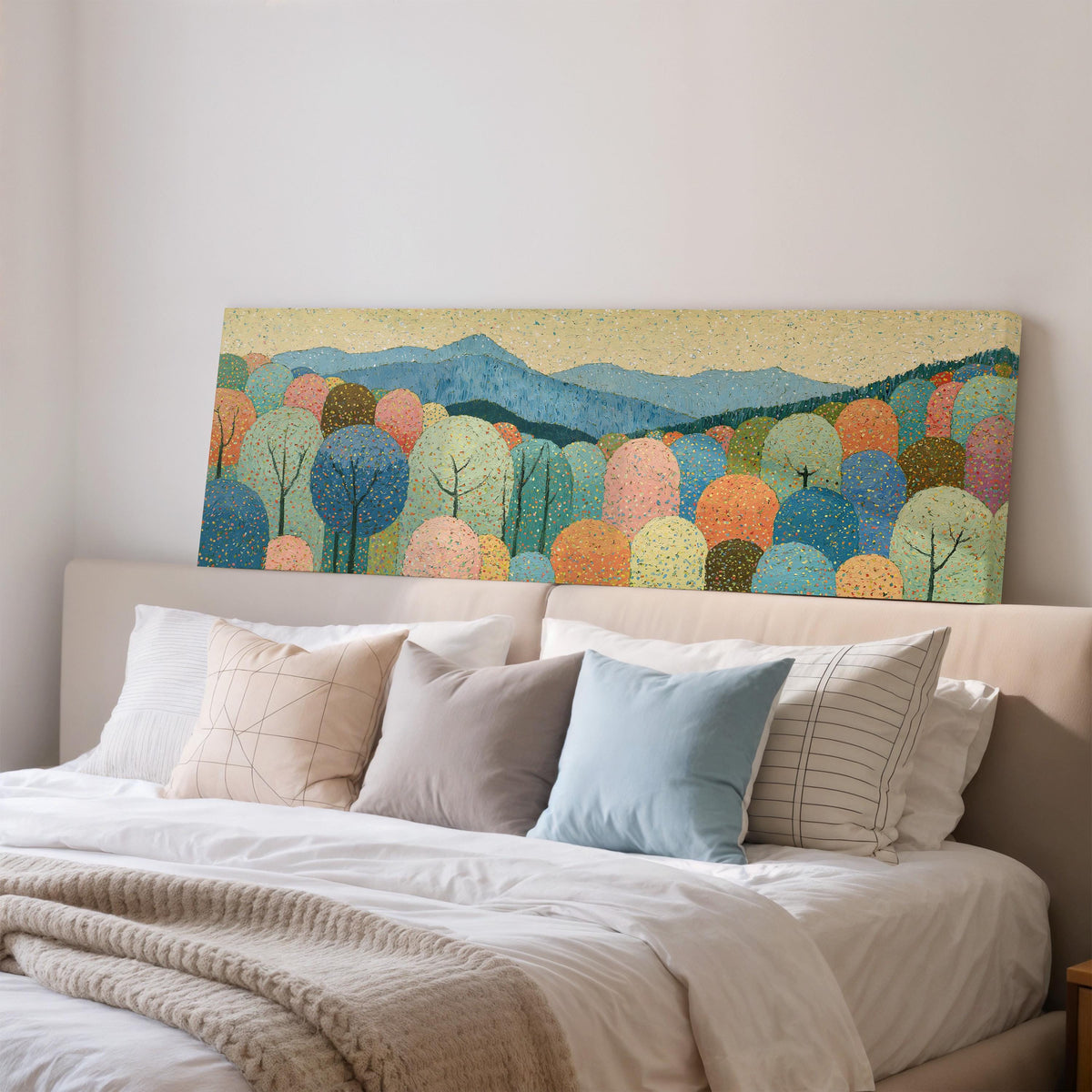 Pastel dotted forest below blue mountains wide panoramic canvas print above a bed in a bedroom