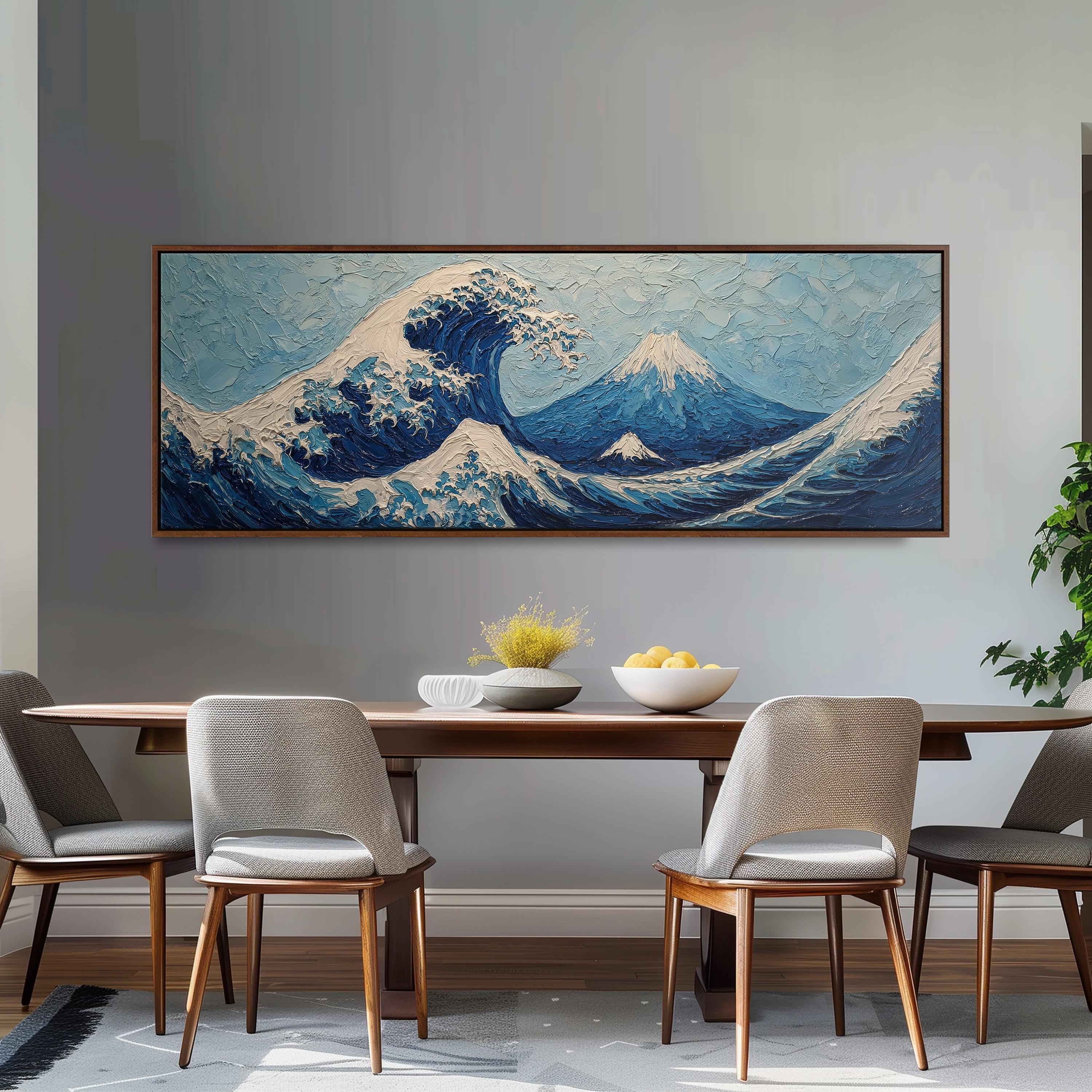 a large painting of a wave on the wall above a wooden dining table with four chairs. The painting is framed and hangs above the table, which has a bowl of fruit and a vase on it.
