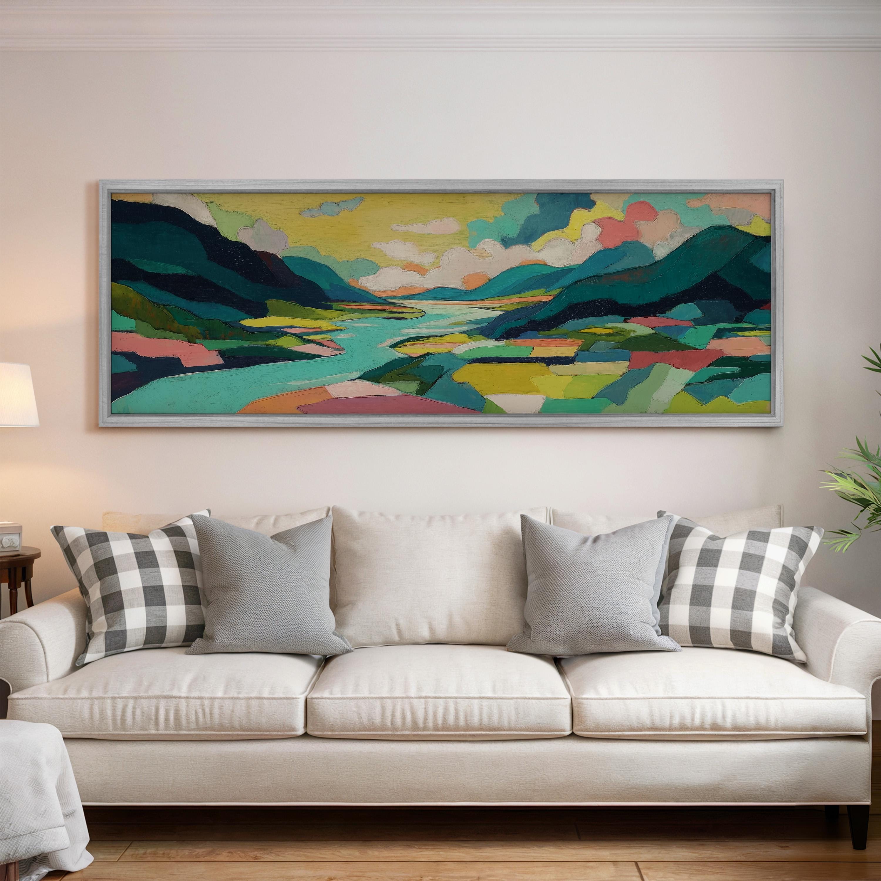 a large, colorful landscape painting hanging on a wall above a white couch with patterned throw pillows.