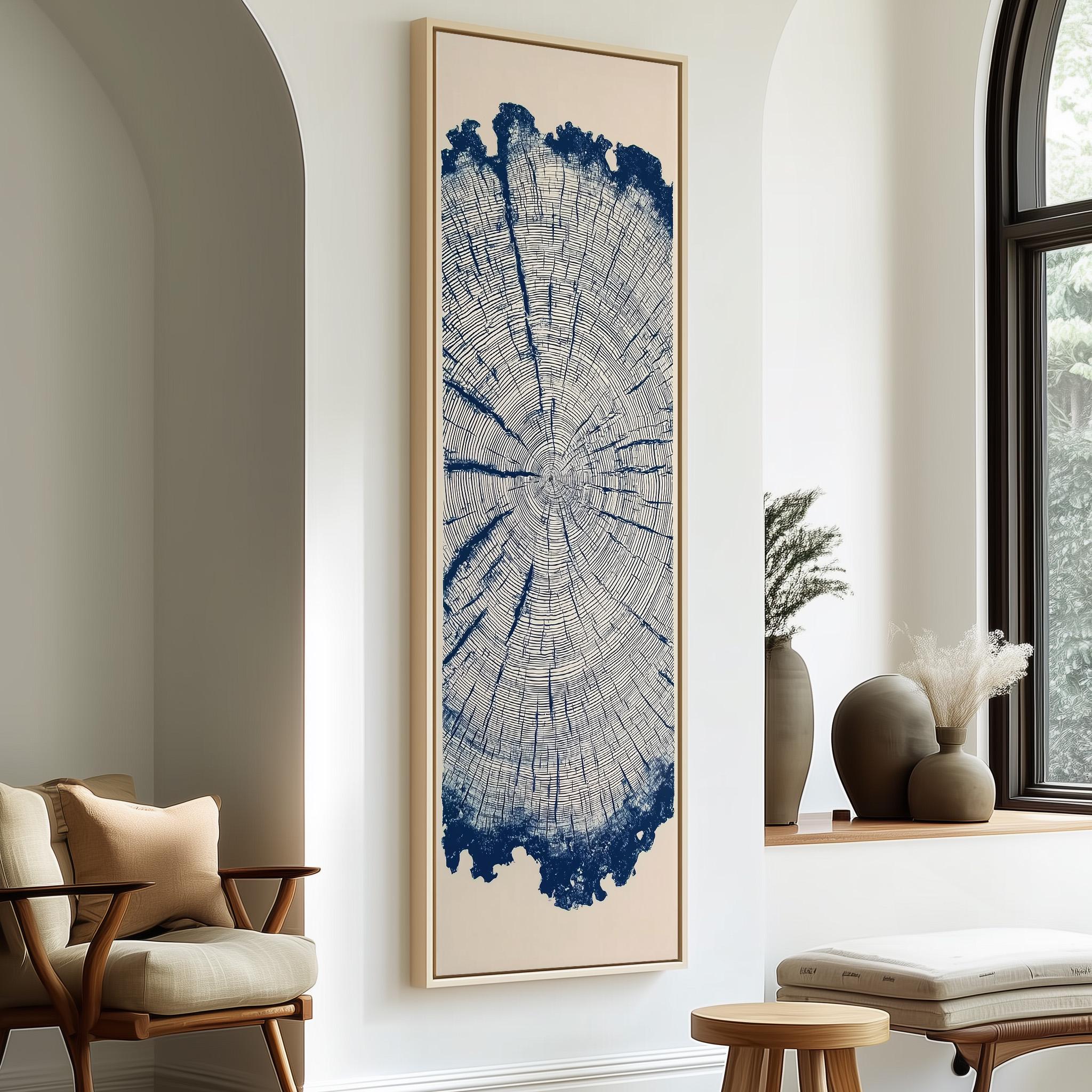 a large framed artwork depicting a tree trunk with a blue and white color scheme, hanging on a white wall in a room with a wooden chair and a small table.