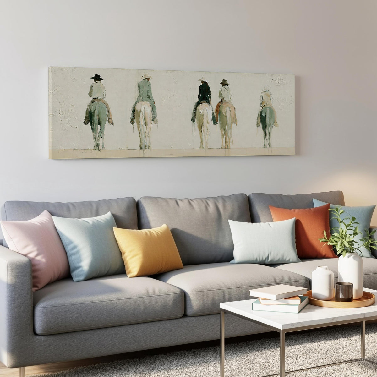 Riders on horseback seen from behind panoramic canvas print above a grey sofa in a living room