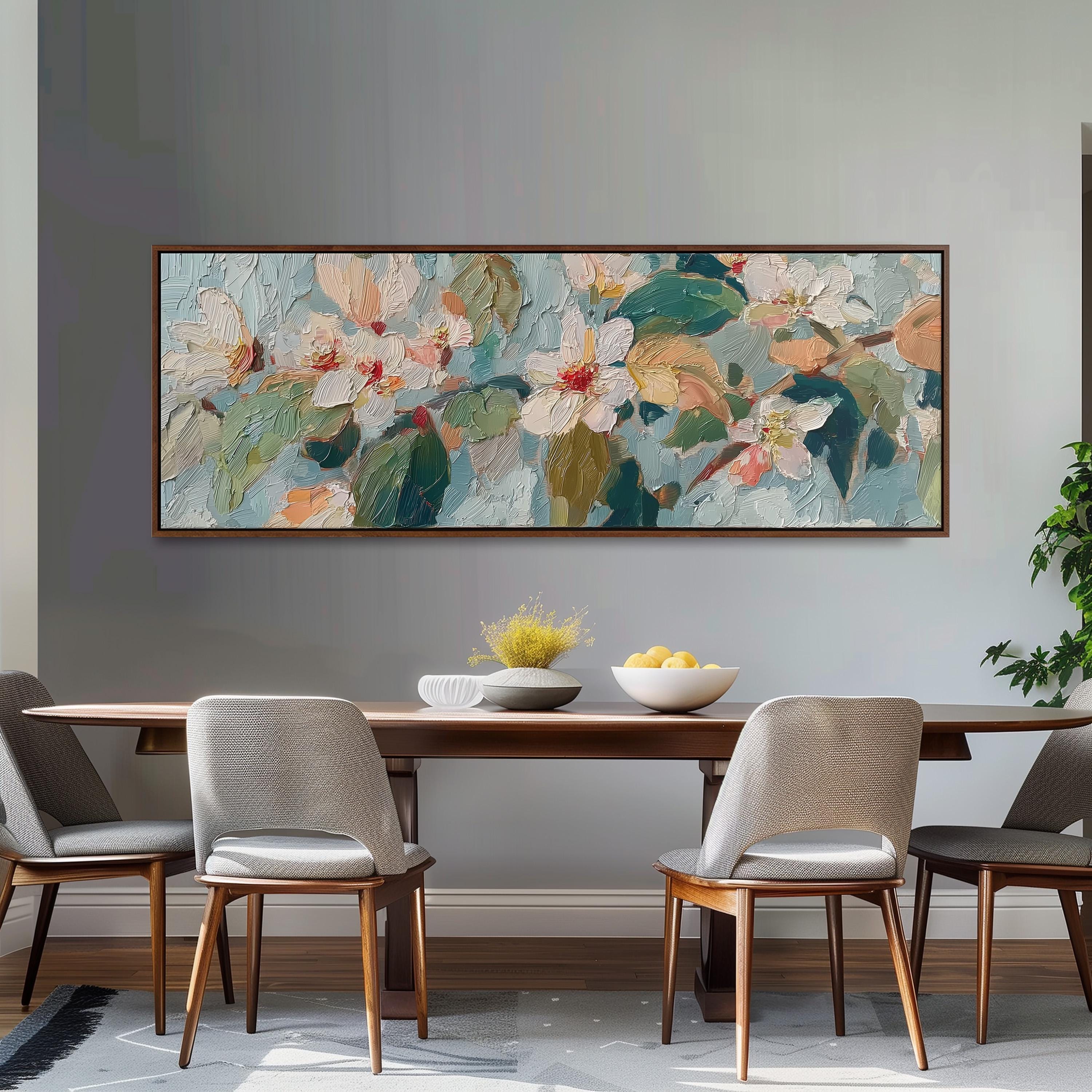 a dining room with a large painting of flowers hanging on the wall above a wooden table with four chairs. The table is set with a bowl of fruit and a vase of flowers, creating a cozy and inviting atmosphere.
