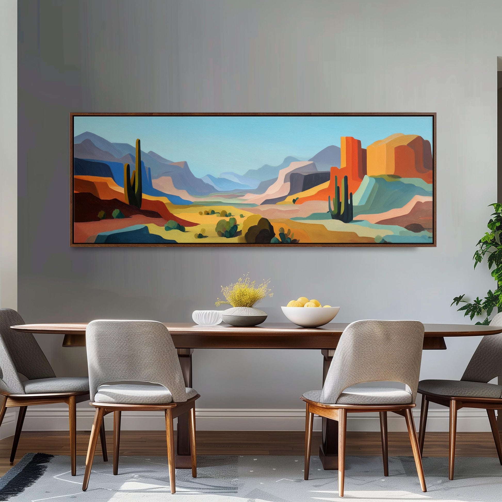 a large, colorful painting of a desert landscape hanging on a wall above a wooden dining table with four chairs.