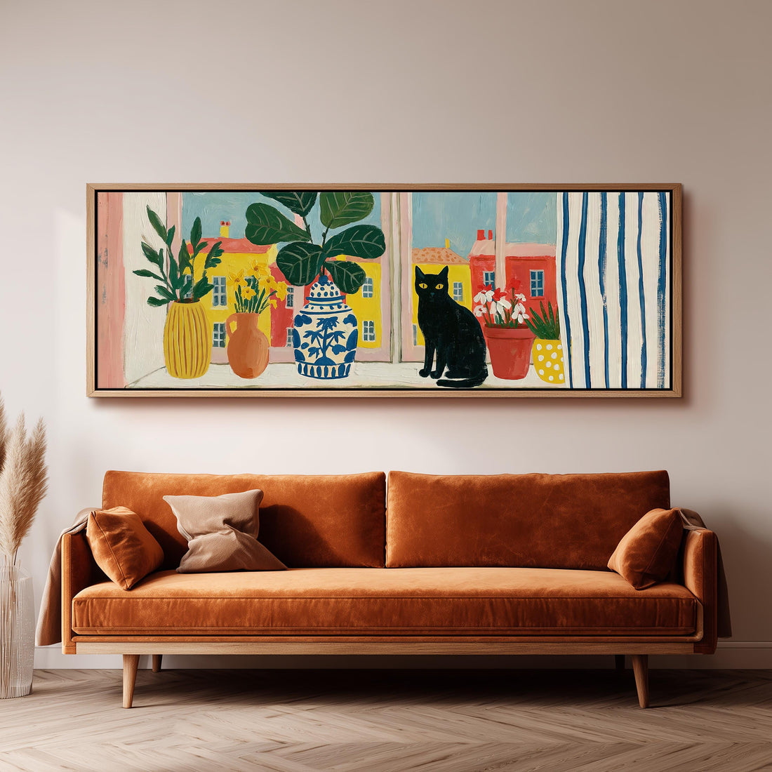 Black cat on a windowsill overlooking a colorful village long horizontal canvas print above a sofa in a living room