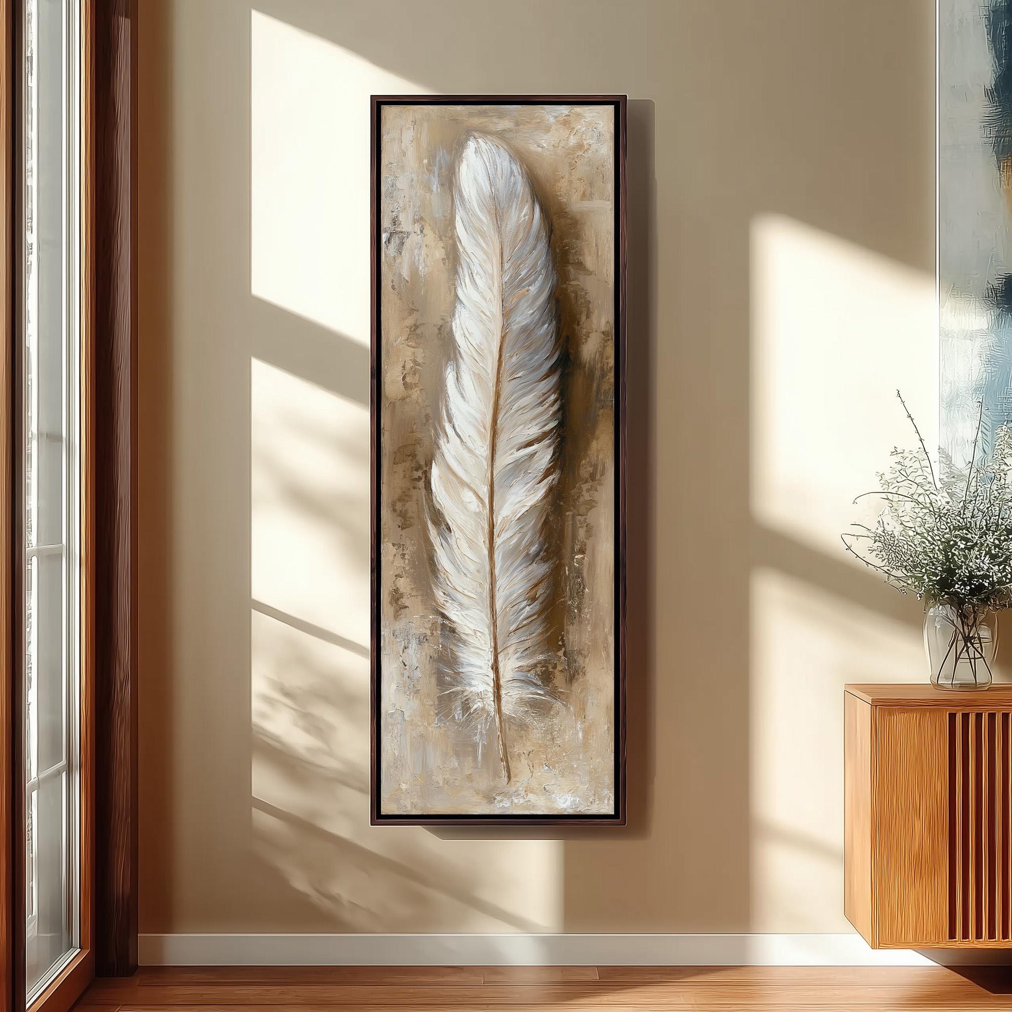 a large framed painting of a feather hanging on a wall in a room with a wooden cabinet and a vase of flowers.