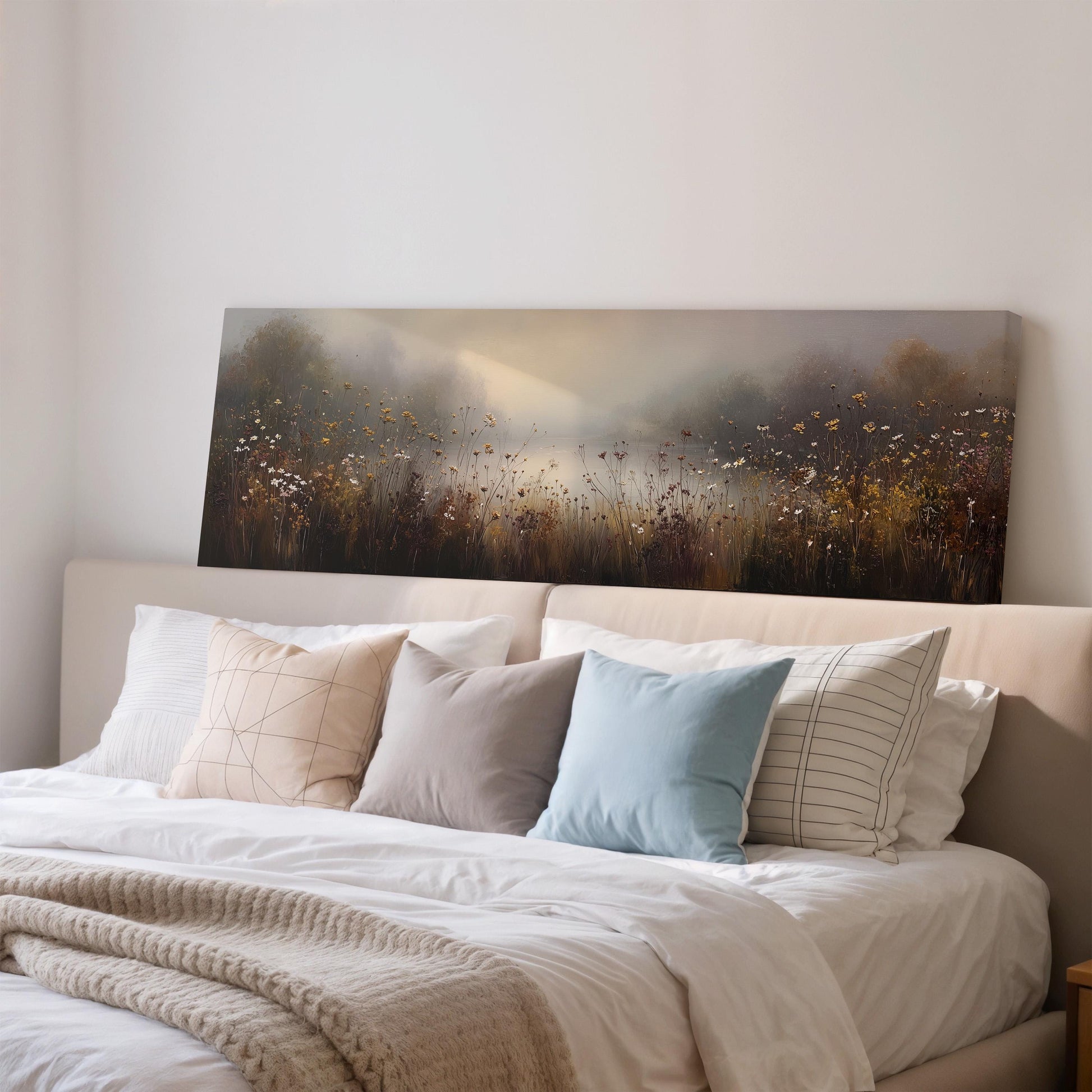 a large painting of a field with flowers hanging above a bed with white sheets and pillows.