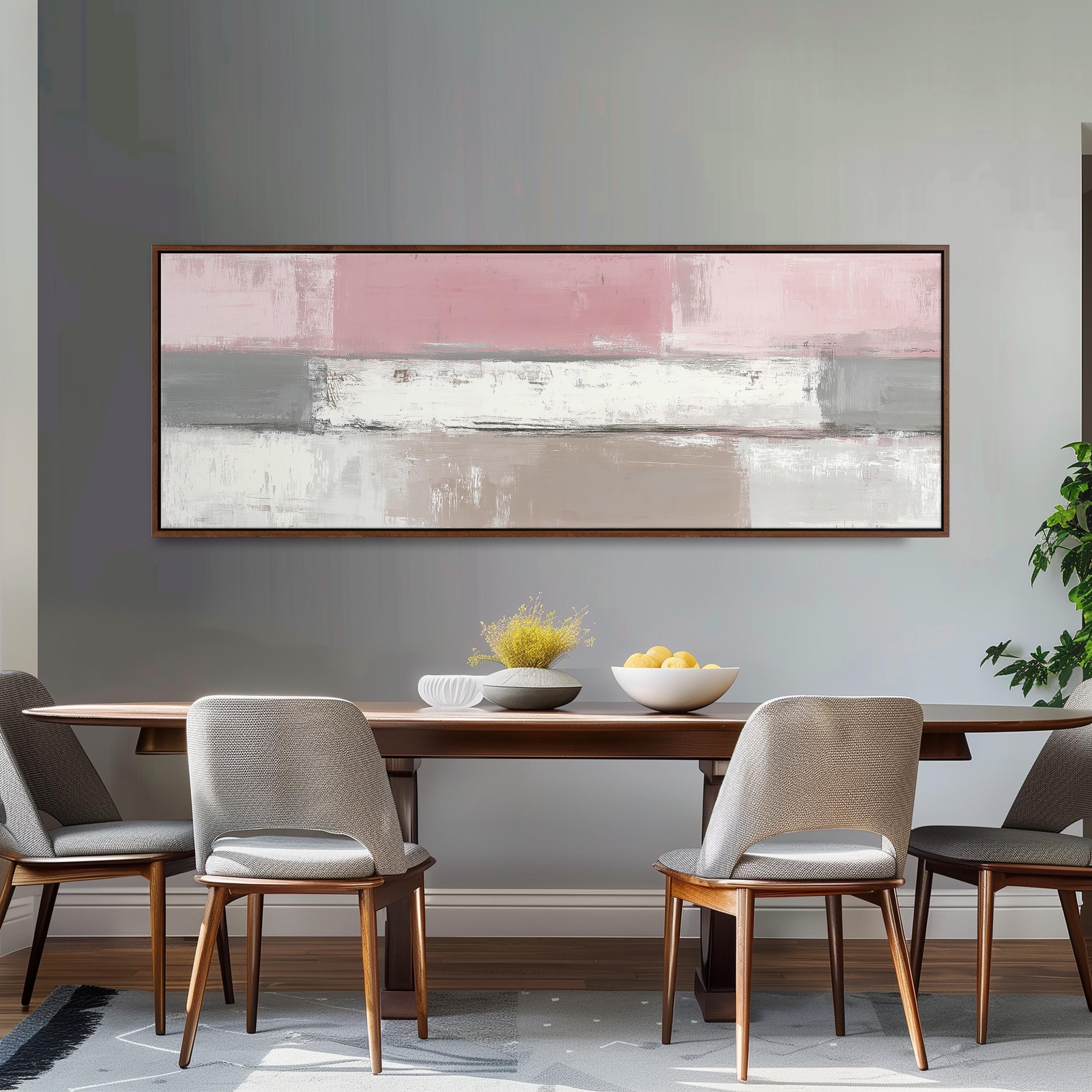 a dining room with a wooden table and four chairs. Above the table, there is a large abstract painting in shades of pink and white. The table is set with a bowl of fruit and a vase of flowers.