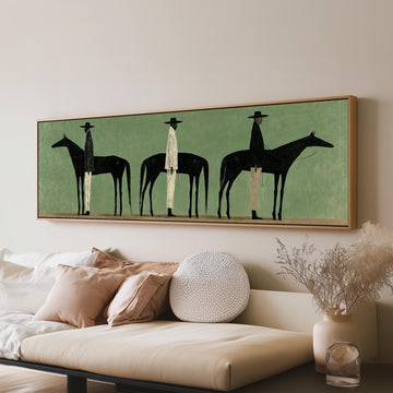 Three stylized cowboys with horses on sage green long horizontal canvas print above a sofa in a living room