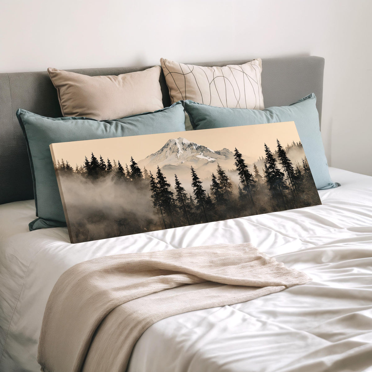 Foggy pine forest below a snowy mountain wide panoramic canvas print laid on a bed to show its size