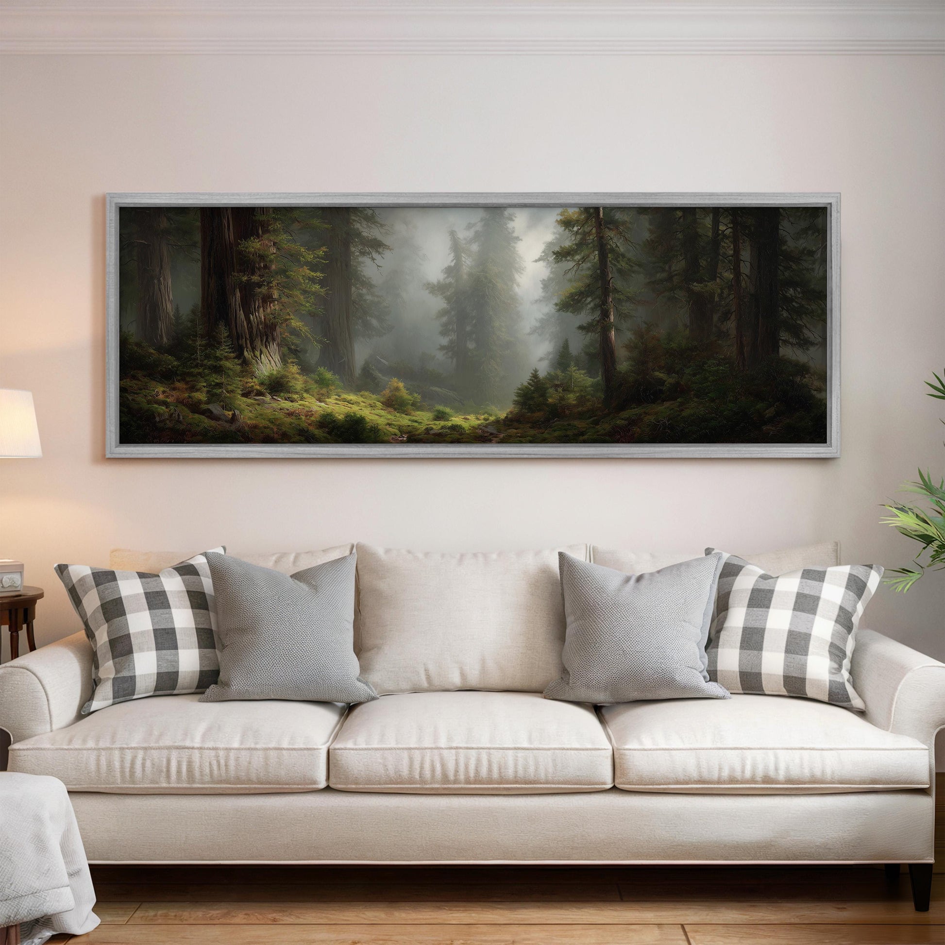a large, framed painting of a forest scene hanging on a wall above a white sofa with gray and white patterned pillows.