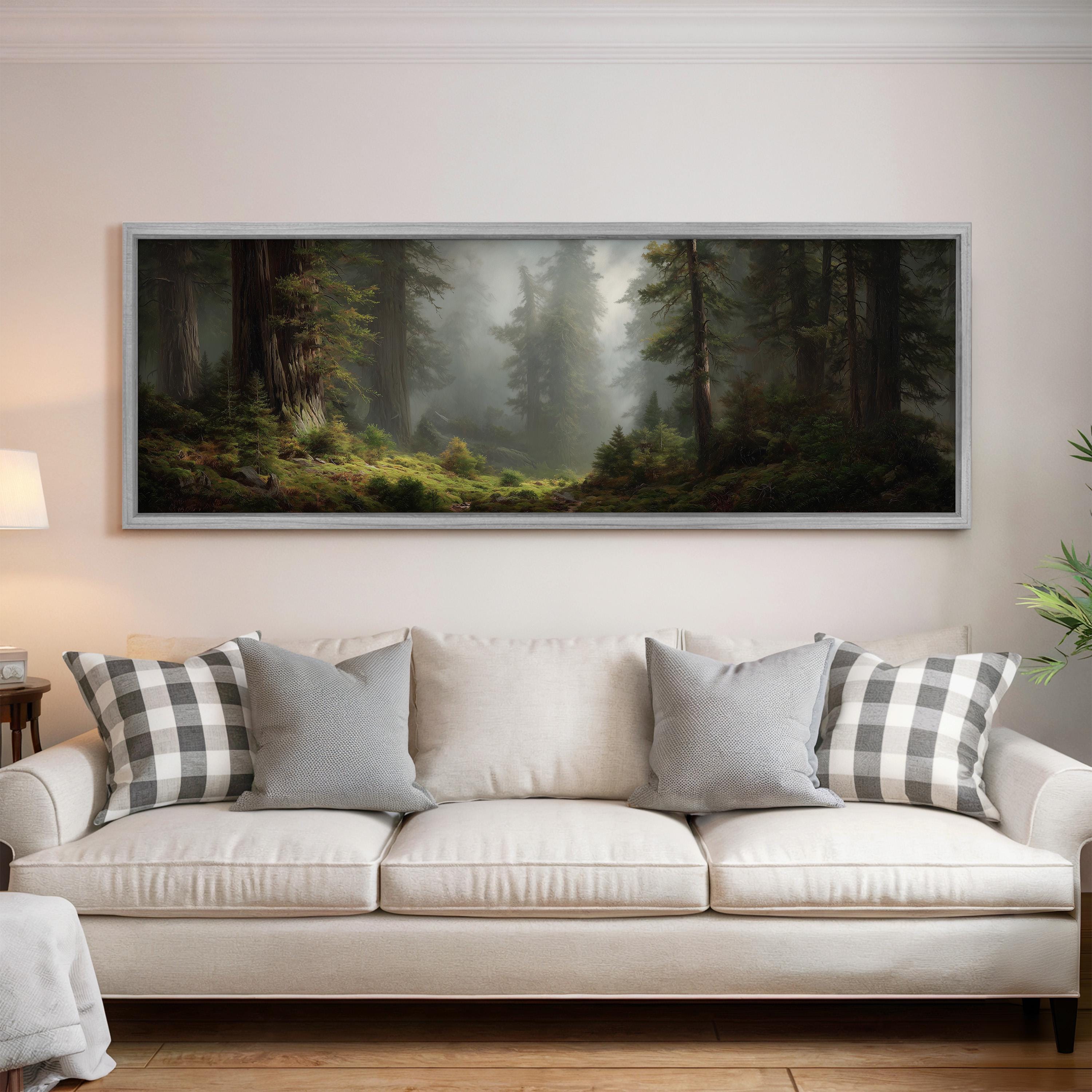 a large, framed painting of a forest scene hanging on a wall above a white sofa with gray and white patterned pillows.