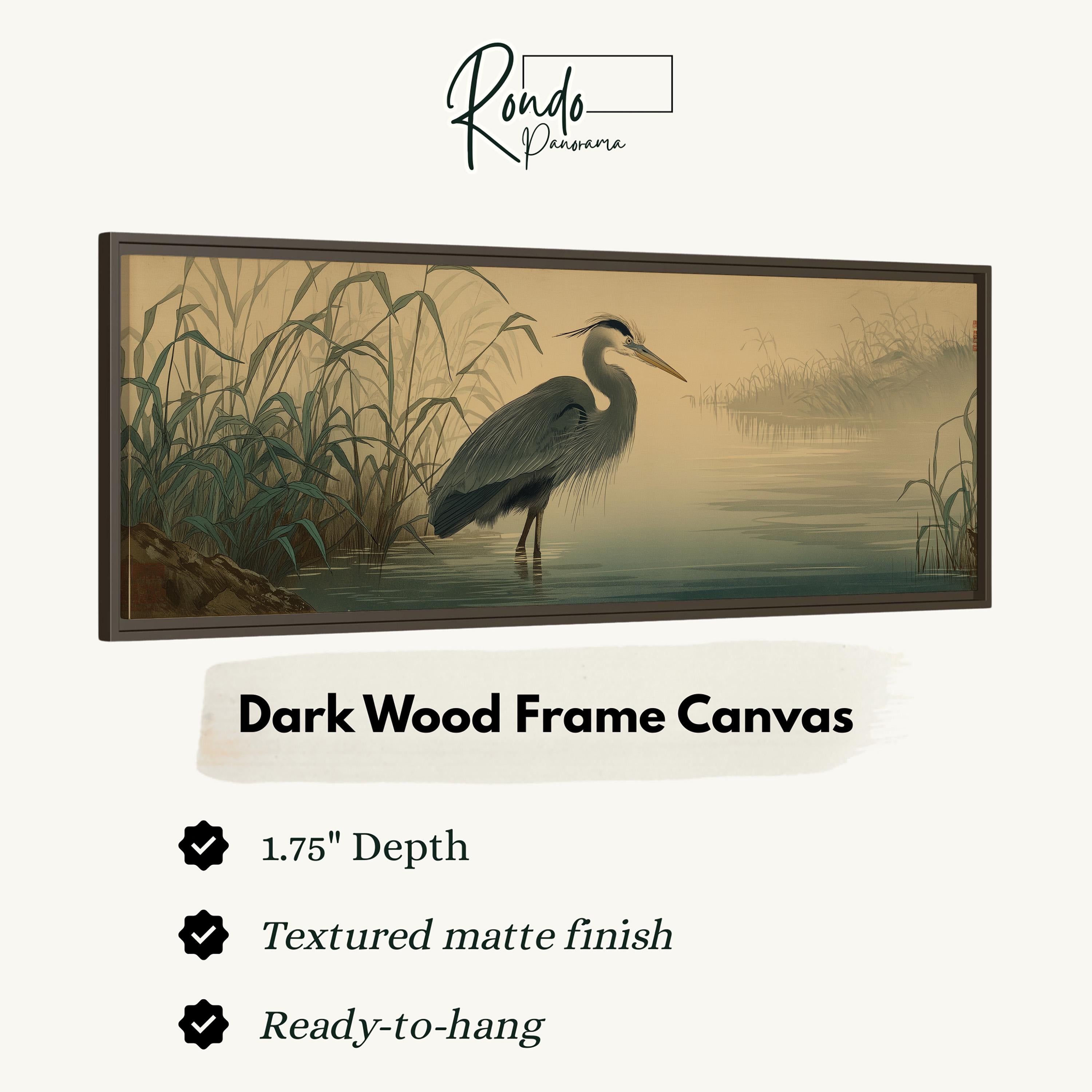 The image is a framed artwork depicting a heron standing in a body of water, with a dark wood frame.