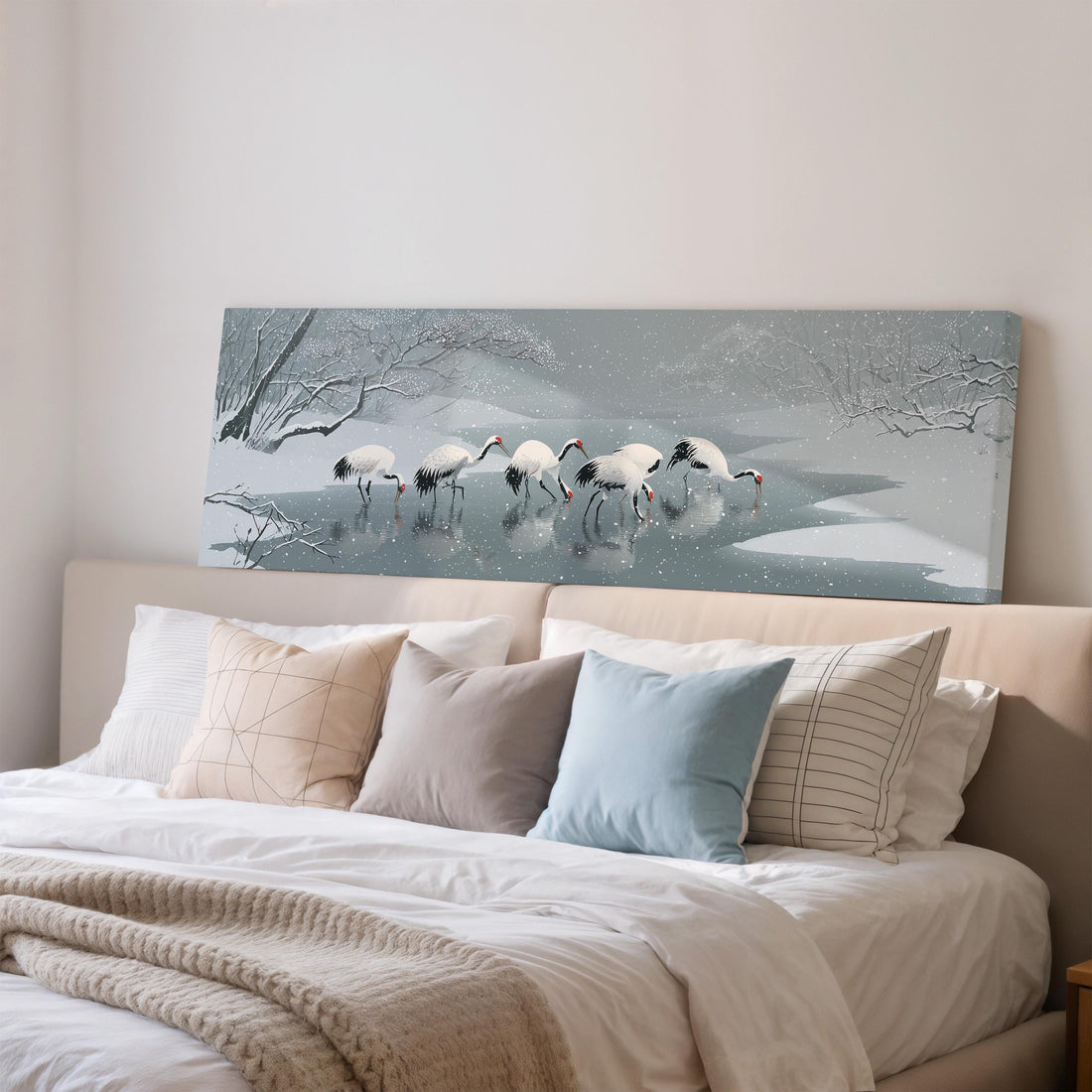 A large framed painting depicting a snowy landscape with a group of white birds standing in the water.