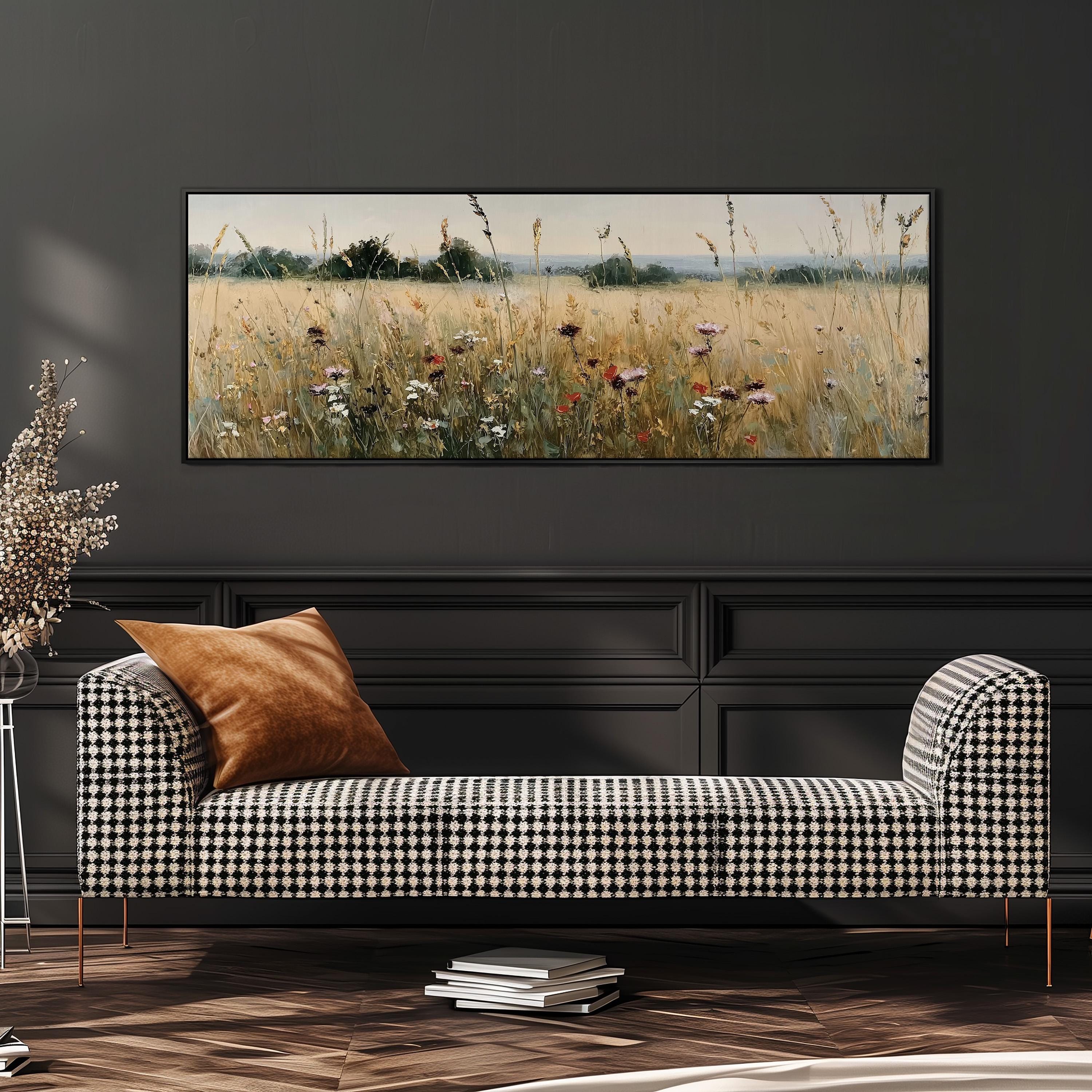 a black and white checkered sofa with a brown throw pillow, set against a dark wall with a large painting of a field of flowers hanging above it.
