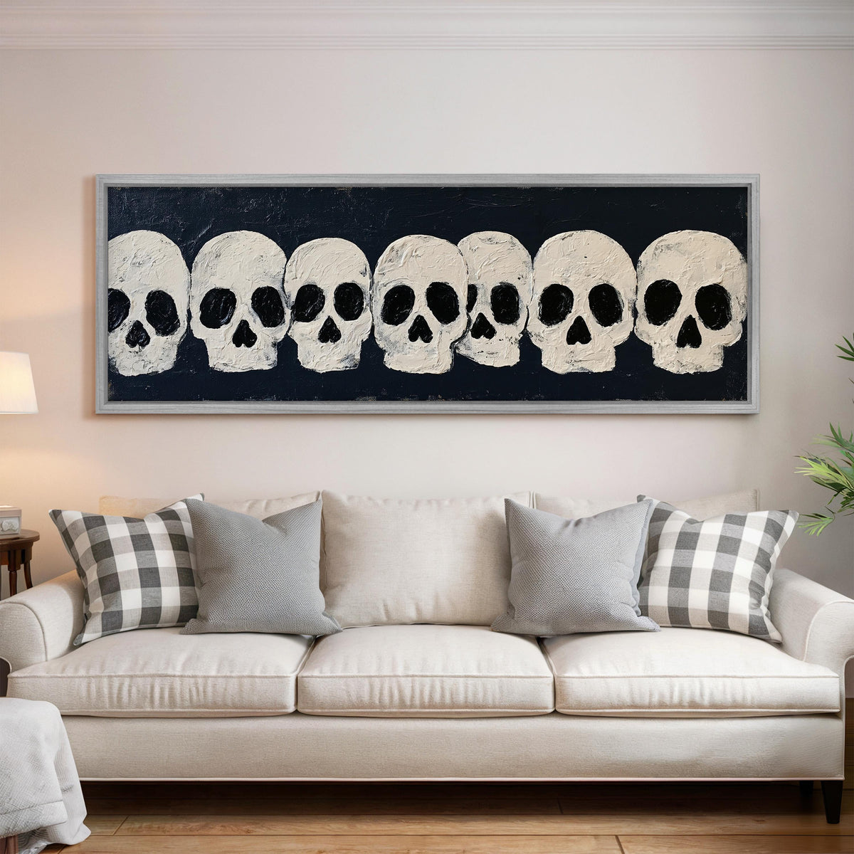 Row of white skulls on navy panoramic canvas print above a white sofa in a bright living room