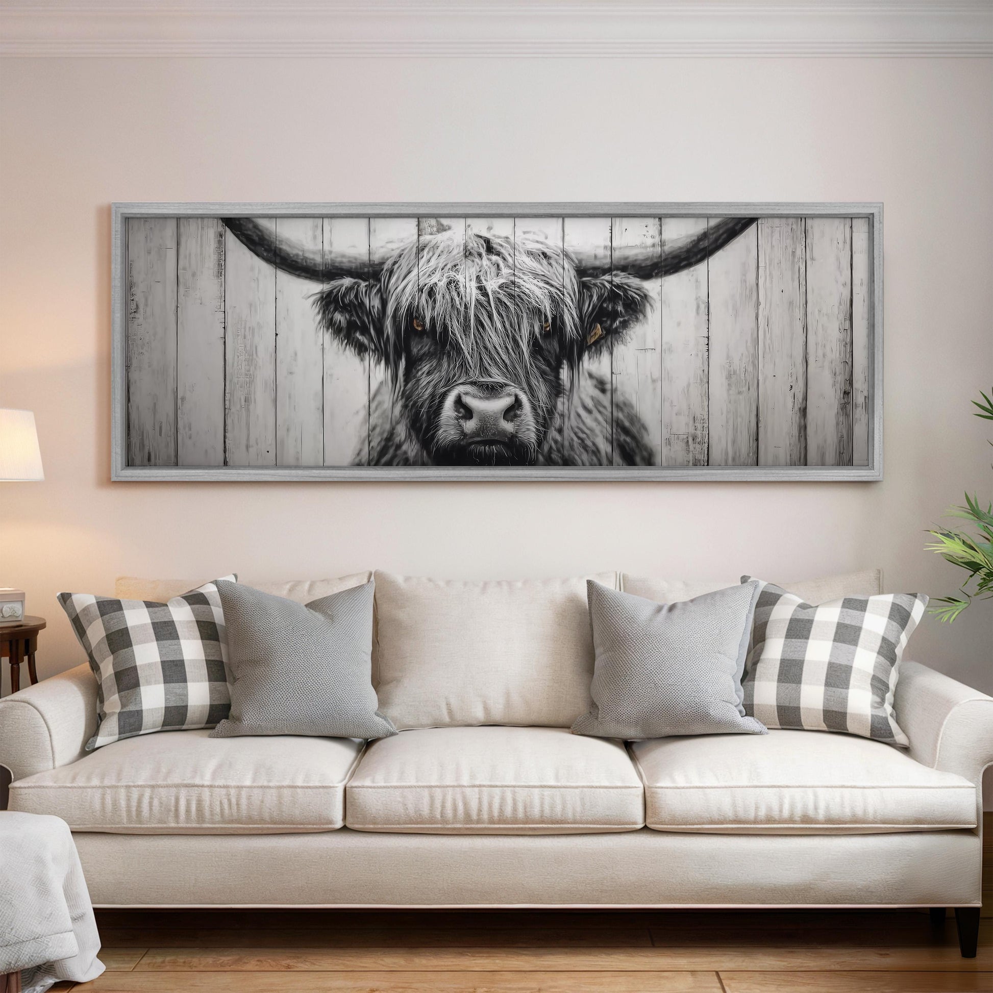 a large framed picture of a cow's face on the wall above a white couch with gray and white pillows.