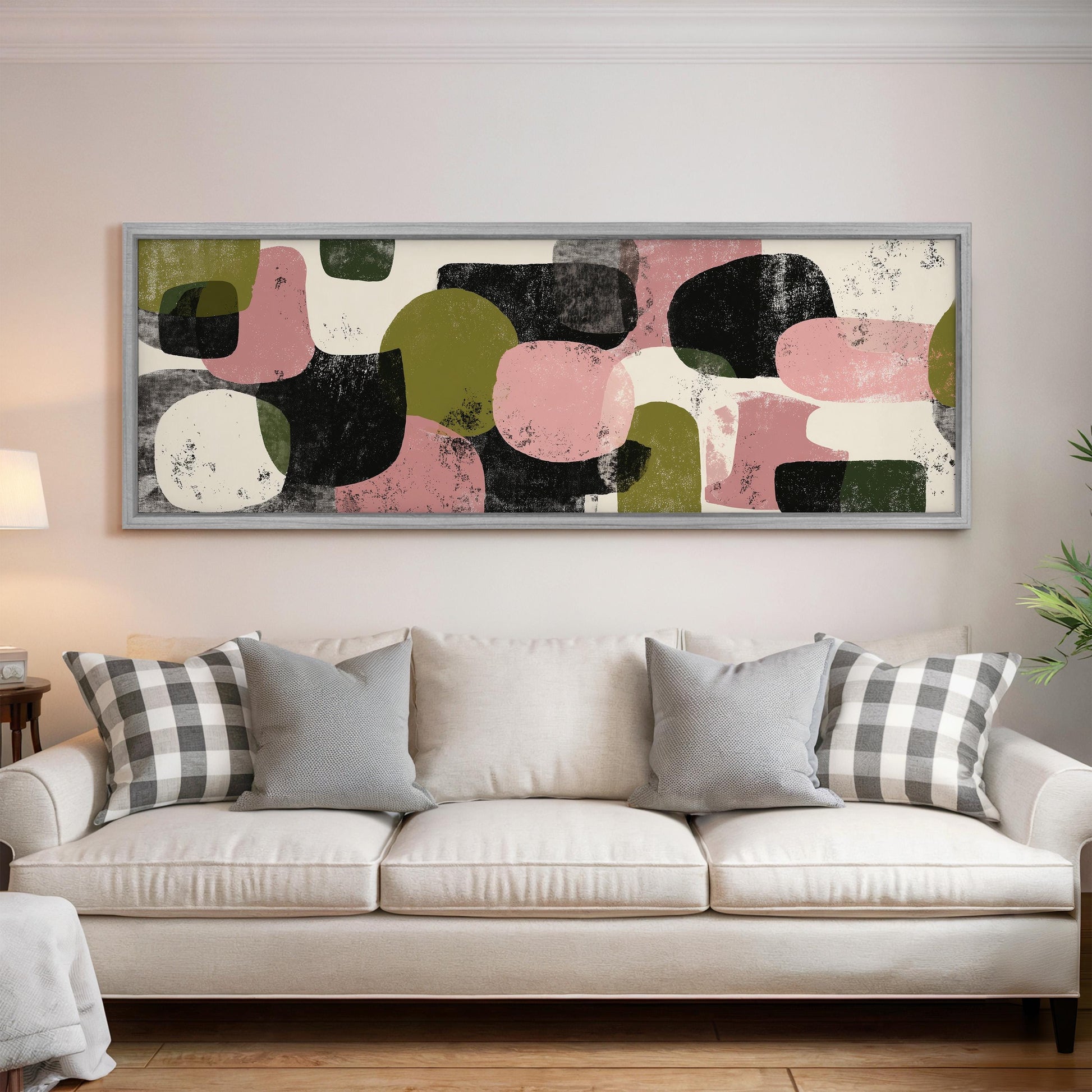 a large abstract painting hanging on a wall above a white couch with gray and white plaid throw pillows.