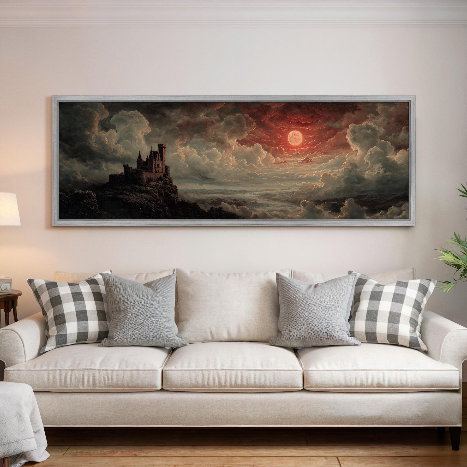 a large painting of a castle on a cliff, with a dramatic sky and clouds in the background. The painting is hung on a wall above a white couch with plaid throw pillows.