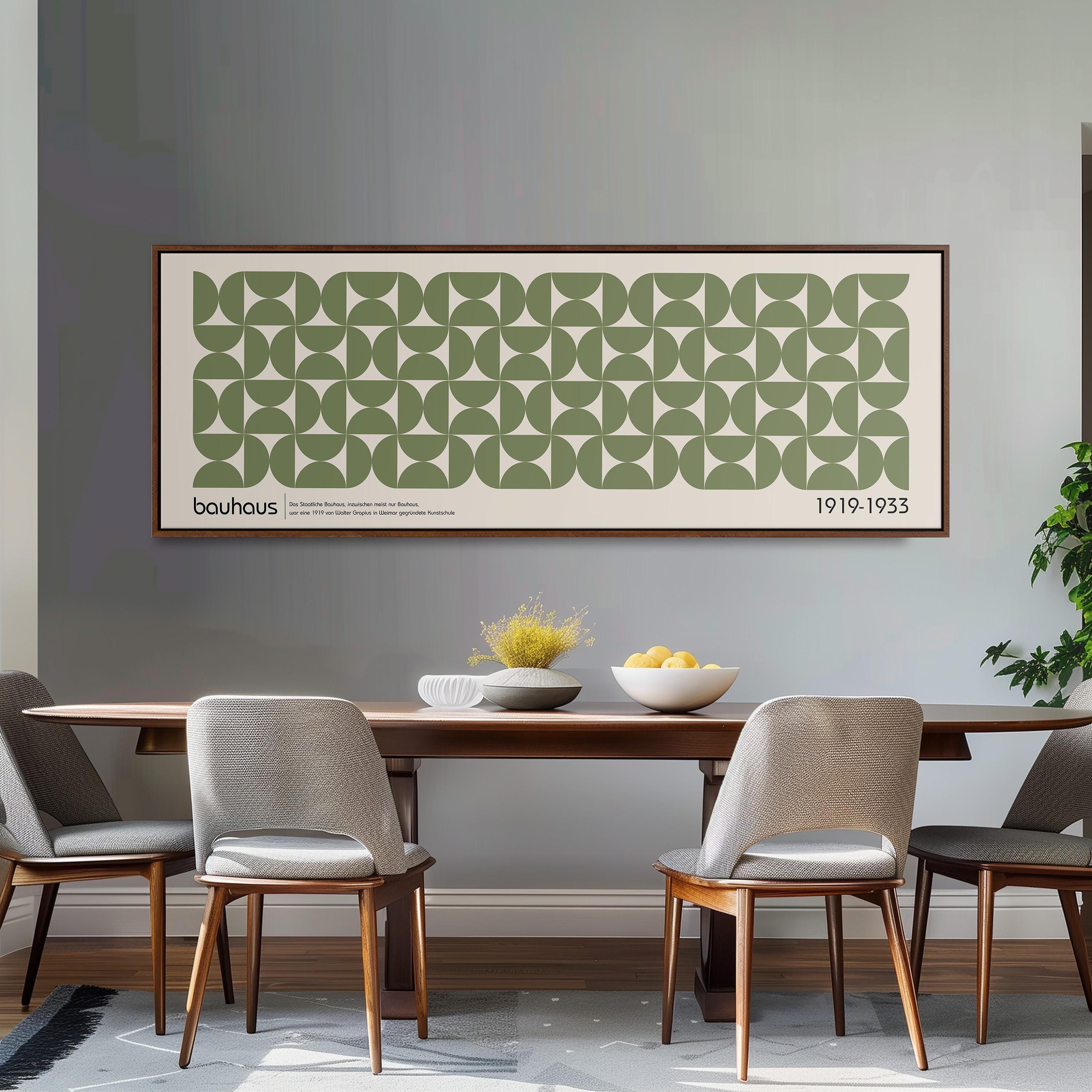 a dining room with a large framed poster of a repeating geometric pattern on the wall above a wooden dining table with four chairs. The table is set with a bowl of fruit and a vase of flowers, creating a cozy and inviting atmosphere.