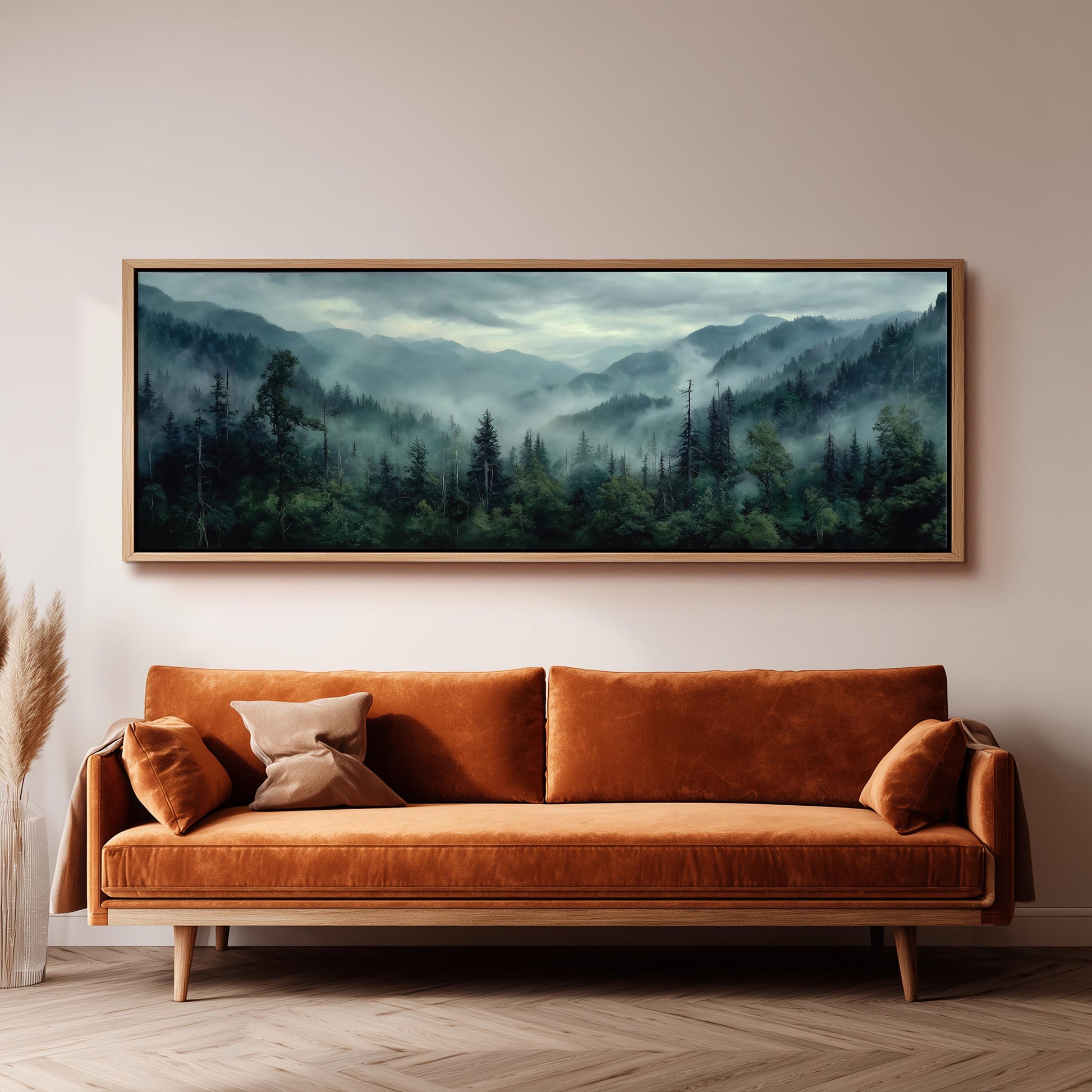 a large, framed painting of a forest landscape hanging on a wall above a brown sofa with orange cushions.
