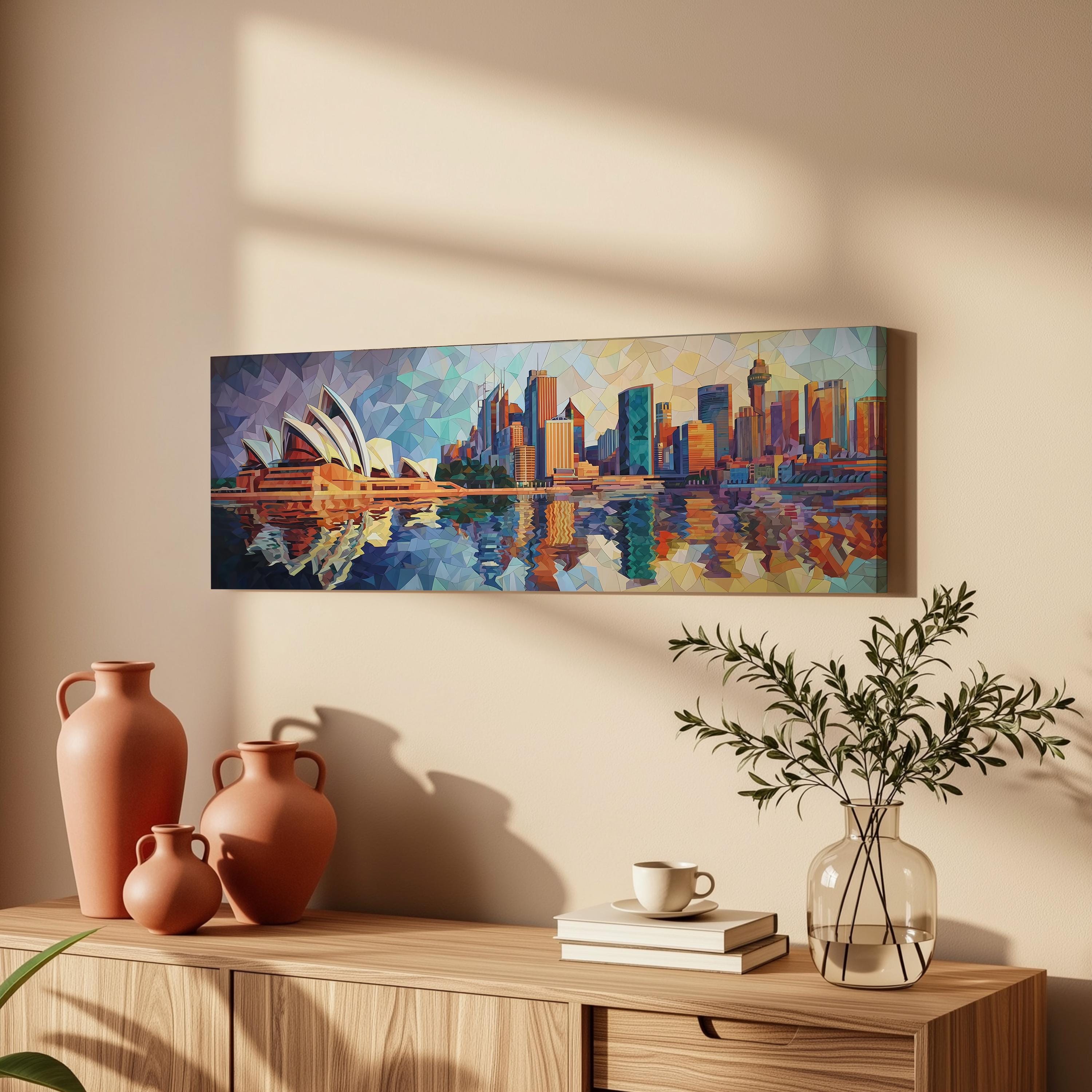 a wooden cabinet with a painting of the Sydney Opera House hanging on the wall above it. The painting is a colorful representation of the iconic landmark, with the city skyline visible in the background. The cabinet also has three orange vases and a glass vase with greenery, as well as a stack of books and a cup on the surface.