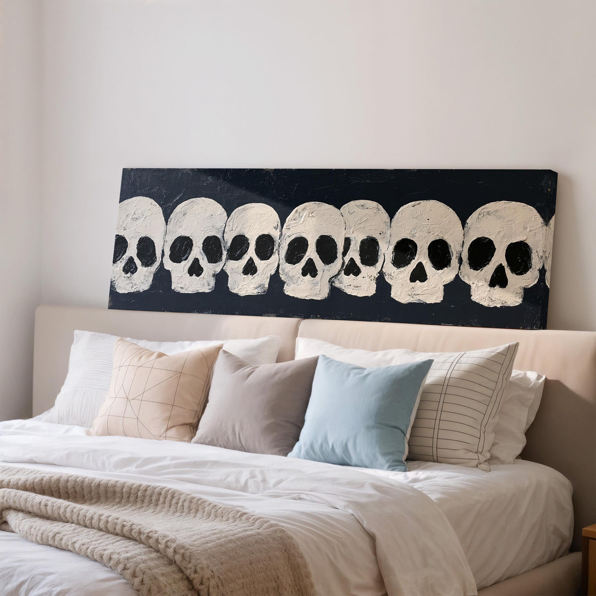 Row of white skulls on navy wide panoramic canvas print above a bed in a bedroom