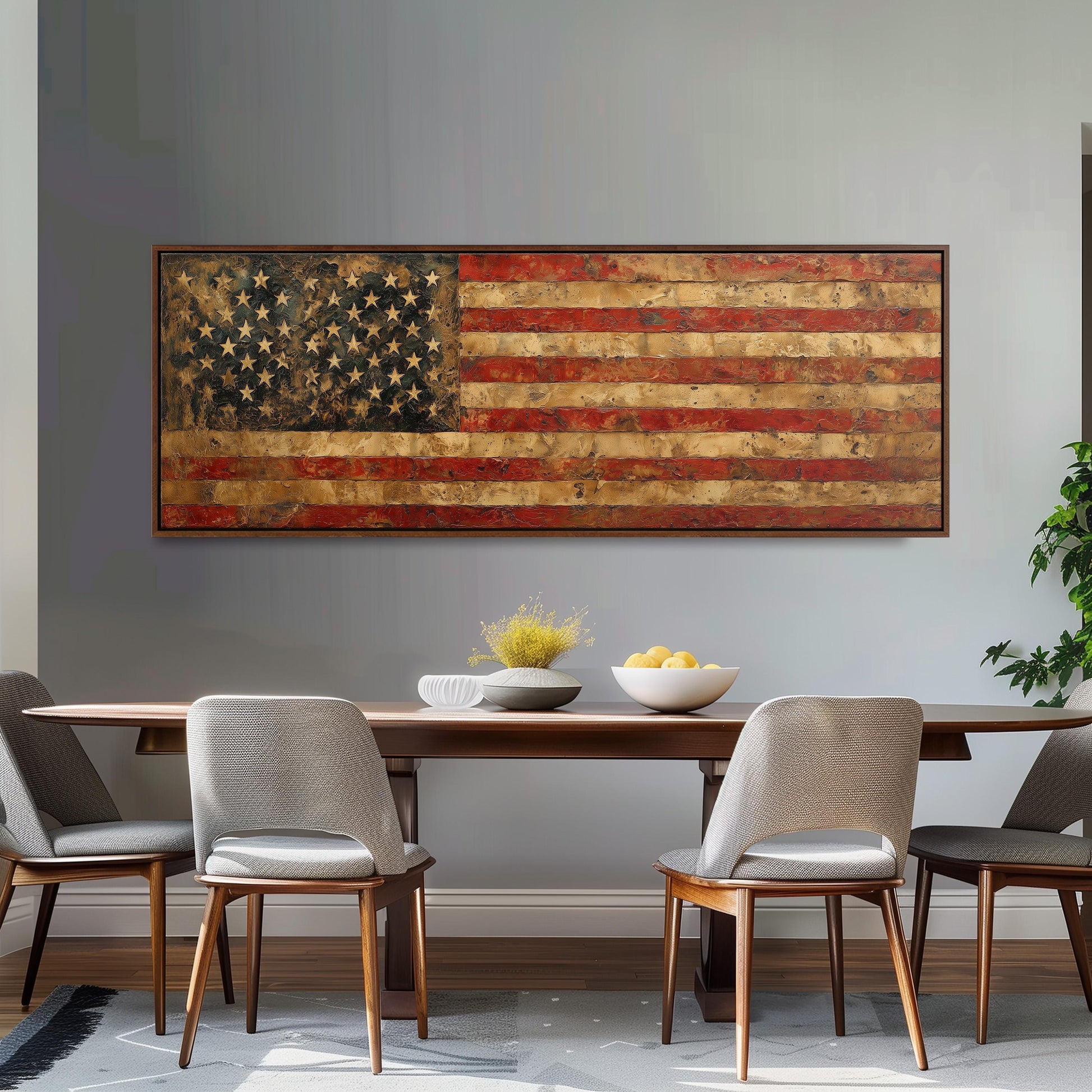 a dining room with a large American flag painting hanging on the wall above a wooden table with four chairs. The table is set with a bowl of fruit and a vase of flowers, creating a welcoming and patriotic atmosphere.