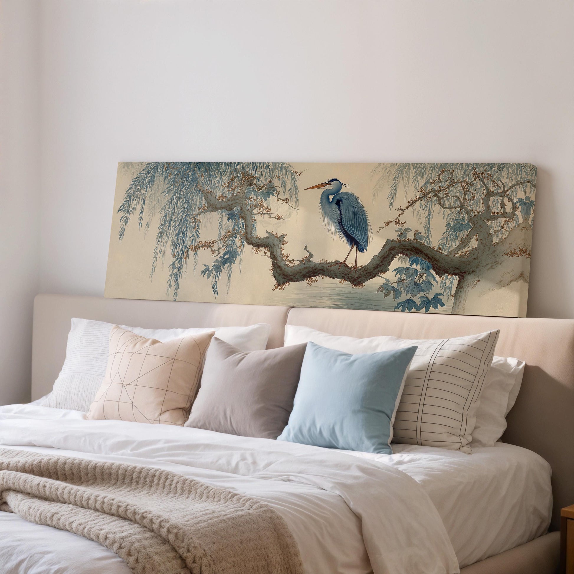 a large painting of a blue heron perched on a branch, displayed on a wall above a bed with white bedding and pillows.