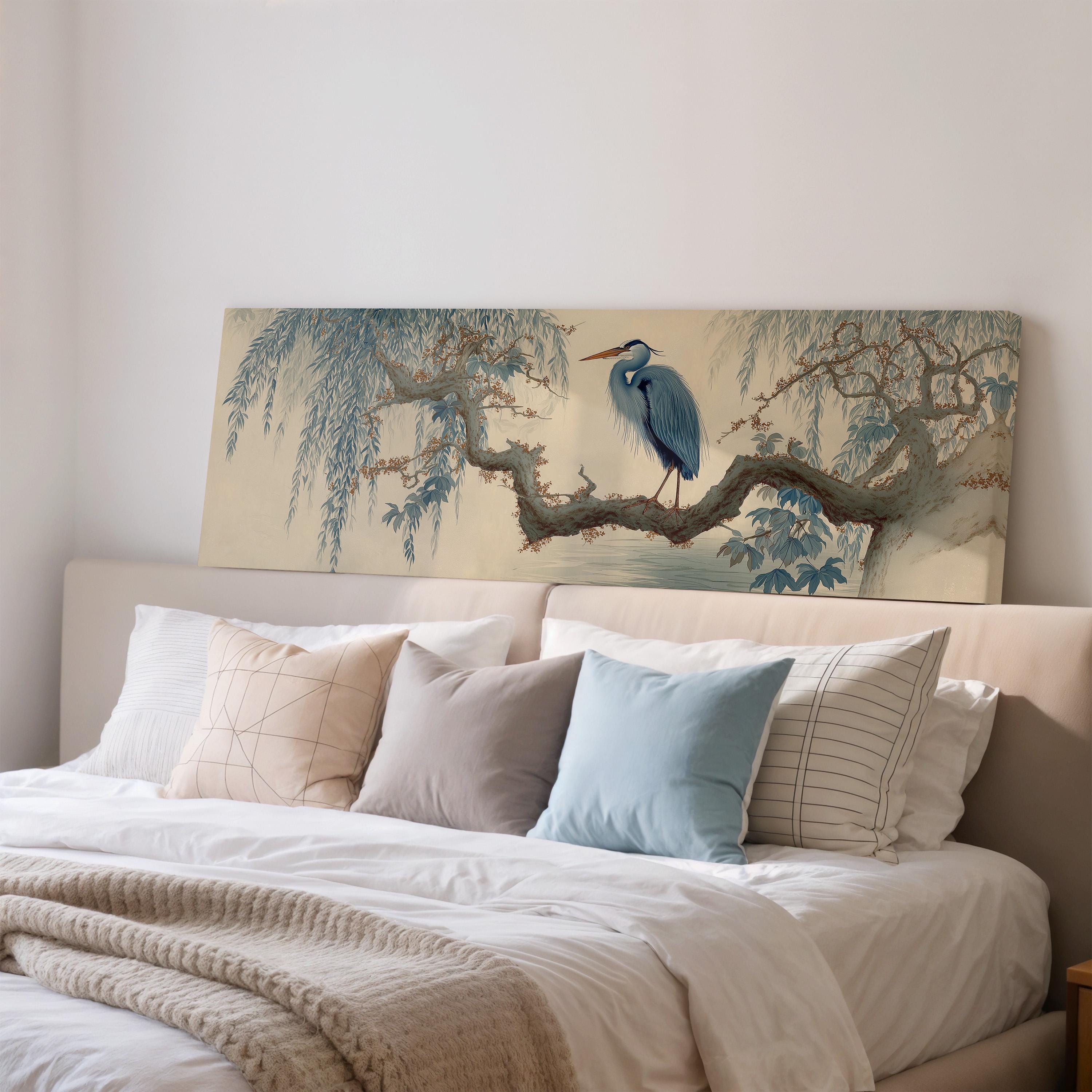 a large painting of a blue heron perched on a branch, displayed on a wall above a bed with white bedding and pillows.