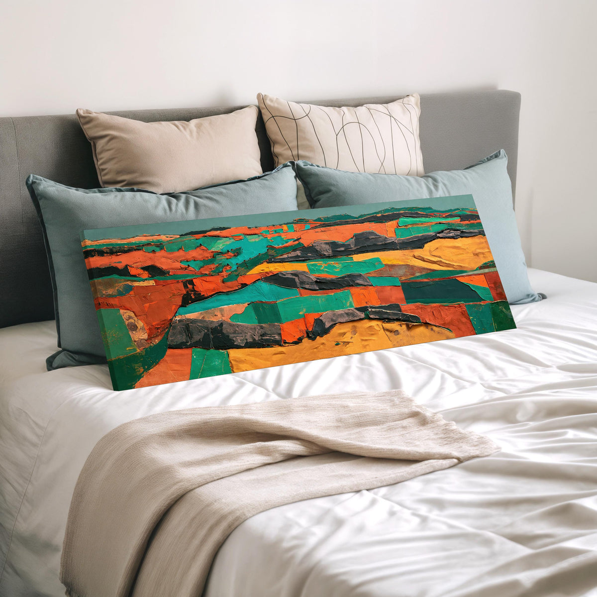 Abstract patchwork terrain in orange and teal wide panoramic canvas print laid on a bed to show its size
