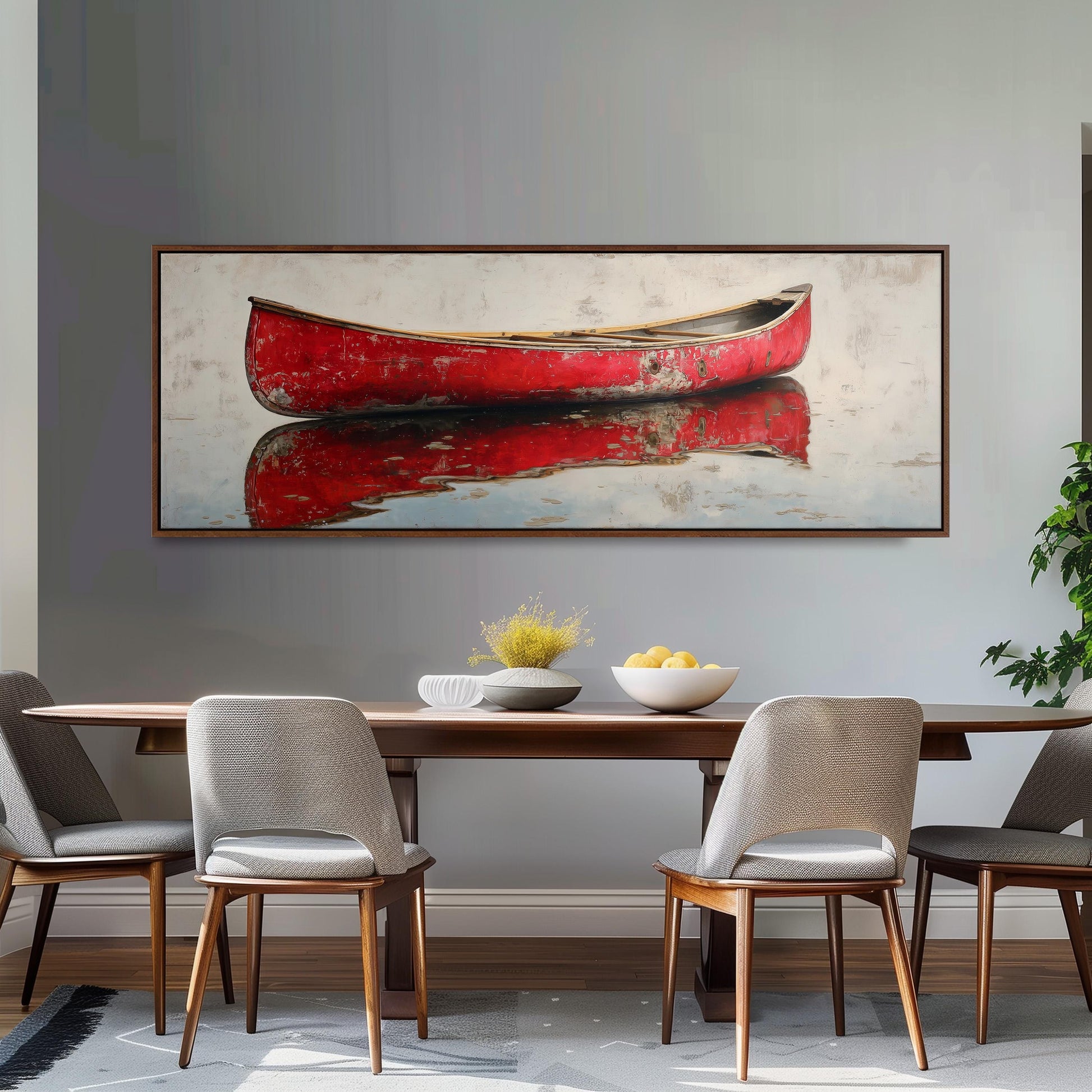 a dining room with a large, framed painting of a red canoe on the wall above a wooden dining table with four chairs. The table is set with a bowl of fruit and a vase of flowers, creating a cozy and inviting atmosphere.