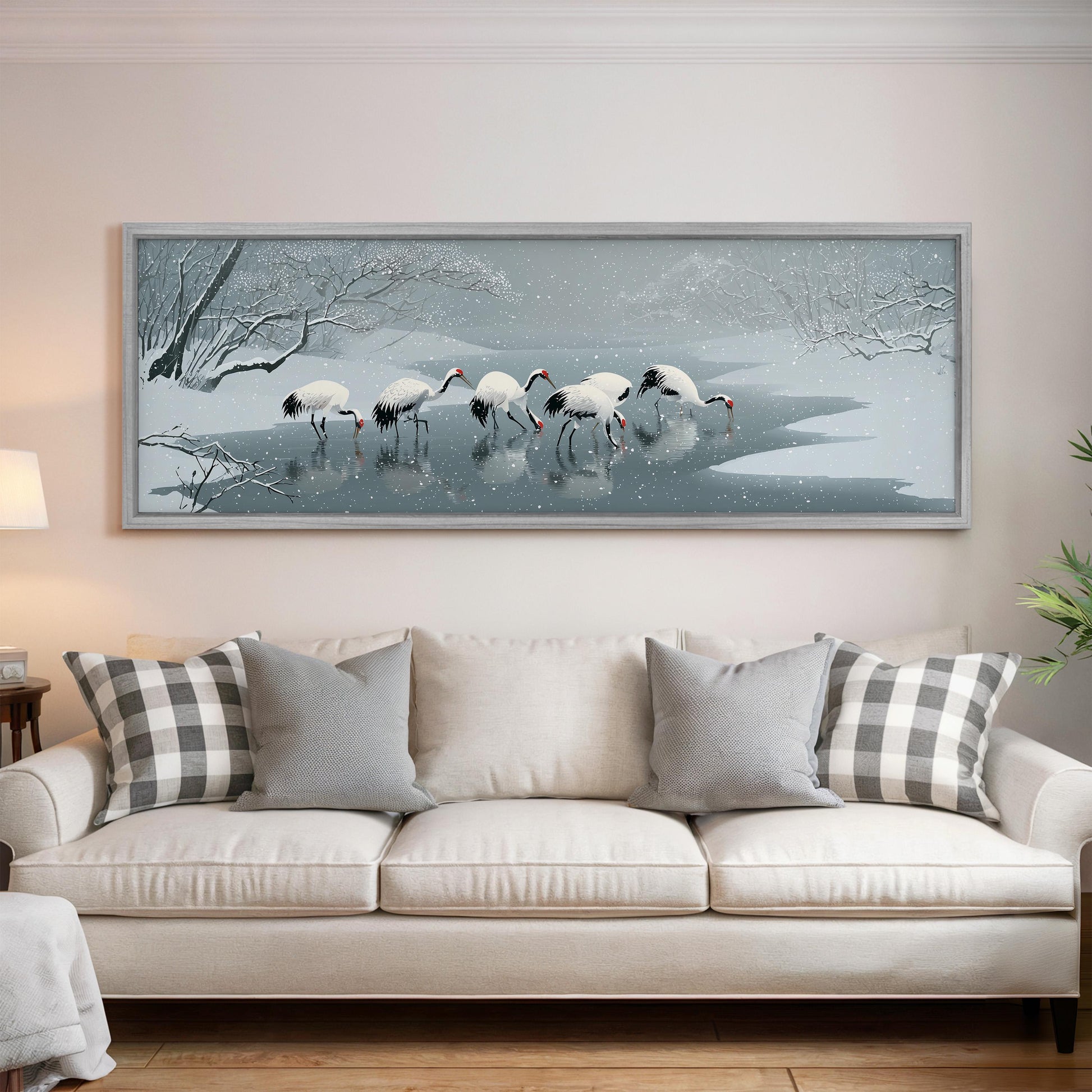 A large framed painting depicting a snowy landscape with a group of white birds standing in the water.
