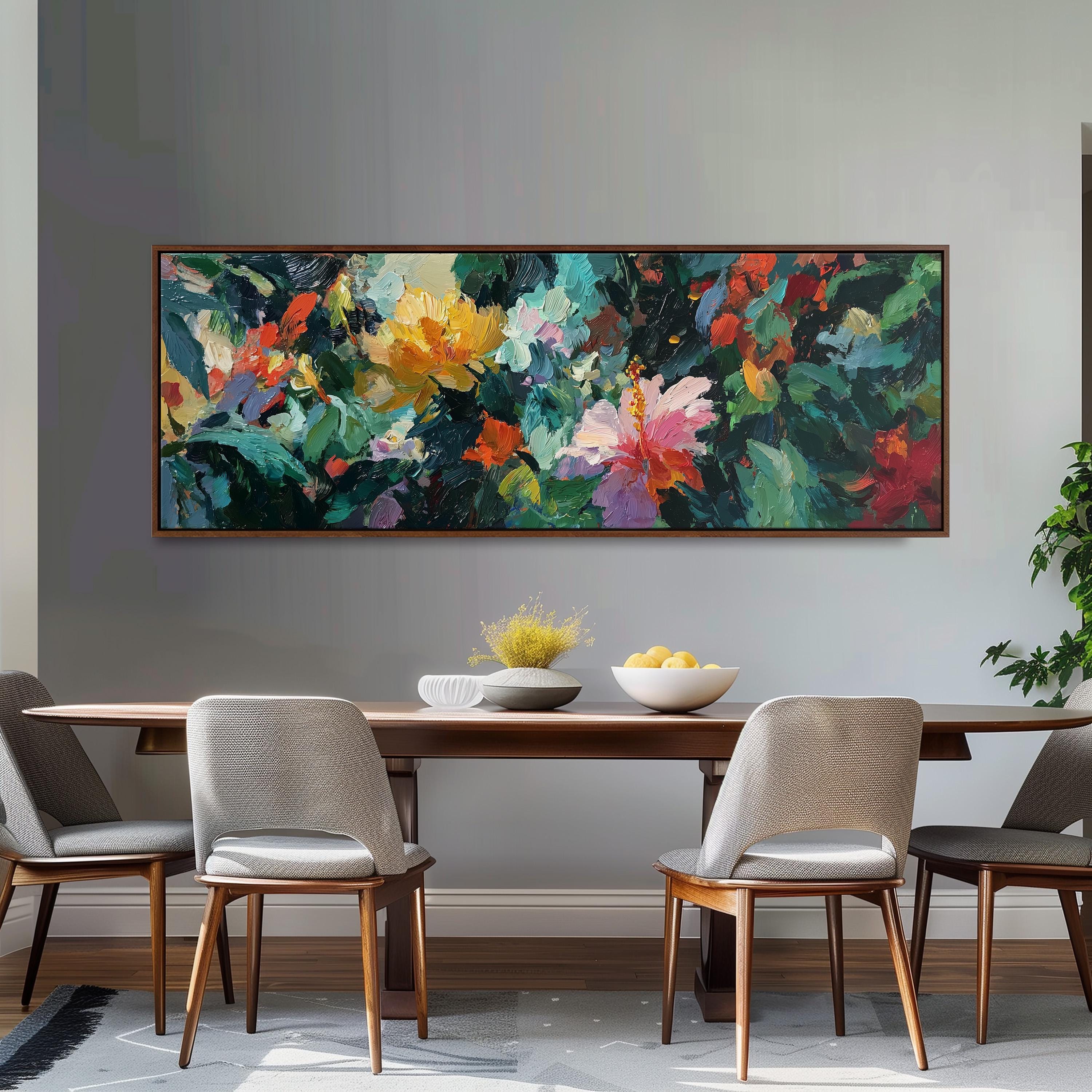 a dining room with a large, colorful painting hanging on the wall above a wooden dining table. The table is set with a bowl of fruit and a vase of flowers, creating a welcoming and vibrant atmosphere. The room is furnished with four chairs, two on each side of the table, and a potted plant is visible in the background.