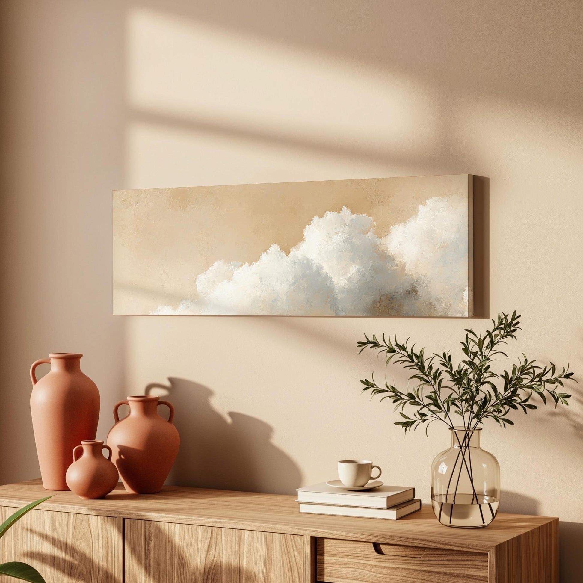 a wooden cabinet with a painting of clouds hanging on the wall above it, along with three orange vases and a glass vase with greenery on the cabinet.