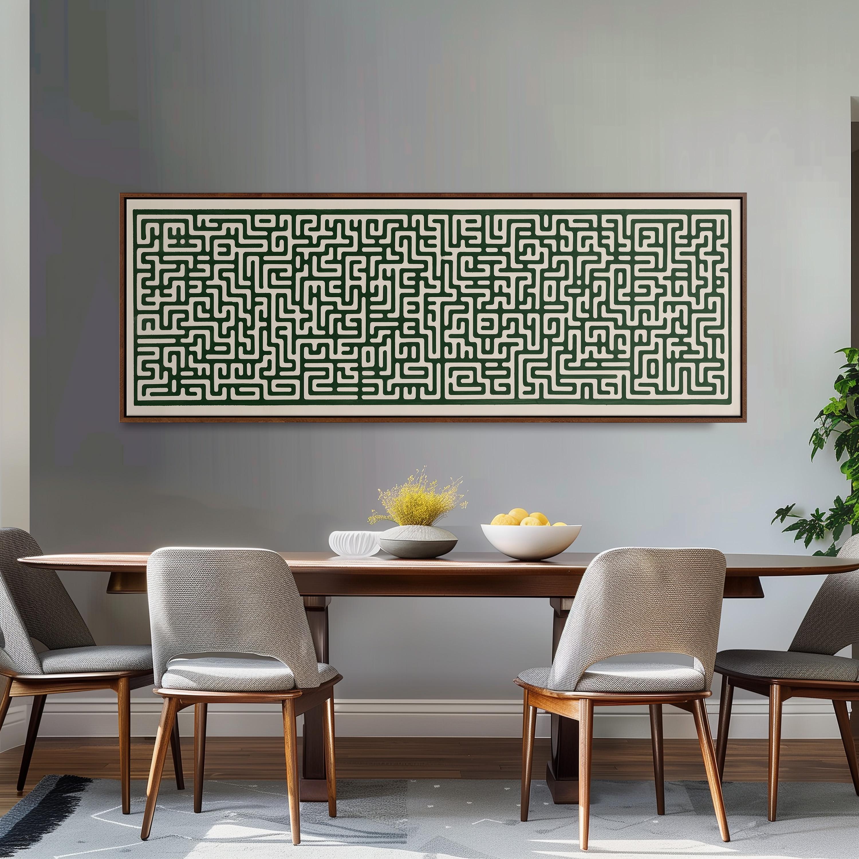 a dining room with a wooden table and four chairs. Above the table, there is a large framed artwork depicting a maze with a green and black color scheme. The artwork is hanging on a gray wall. On the table, there is a bowl of fruit and a vase of flowers.