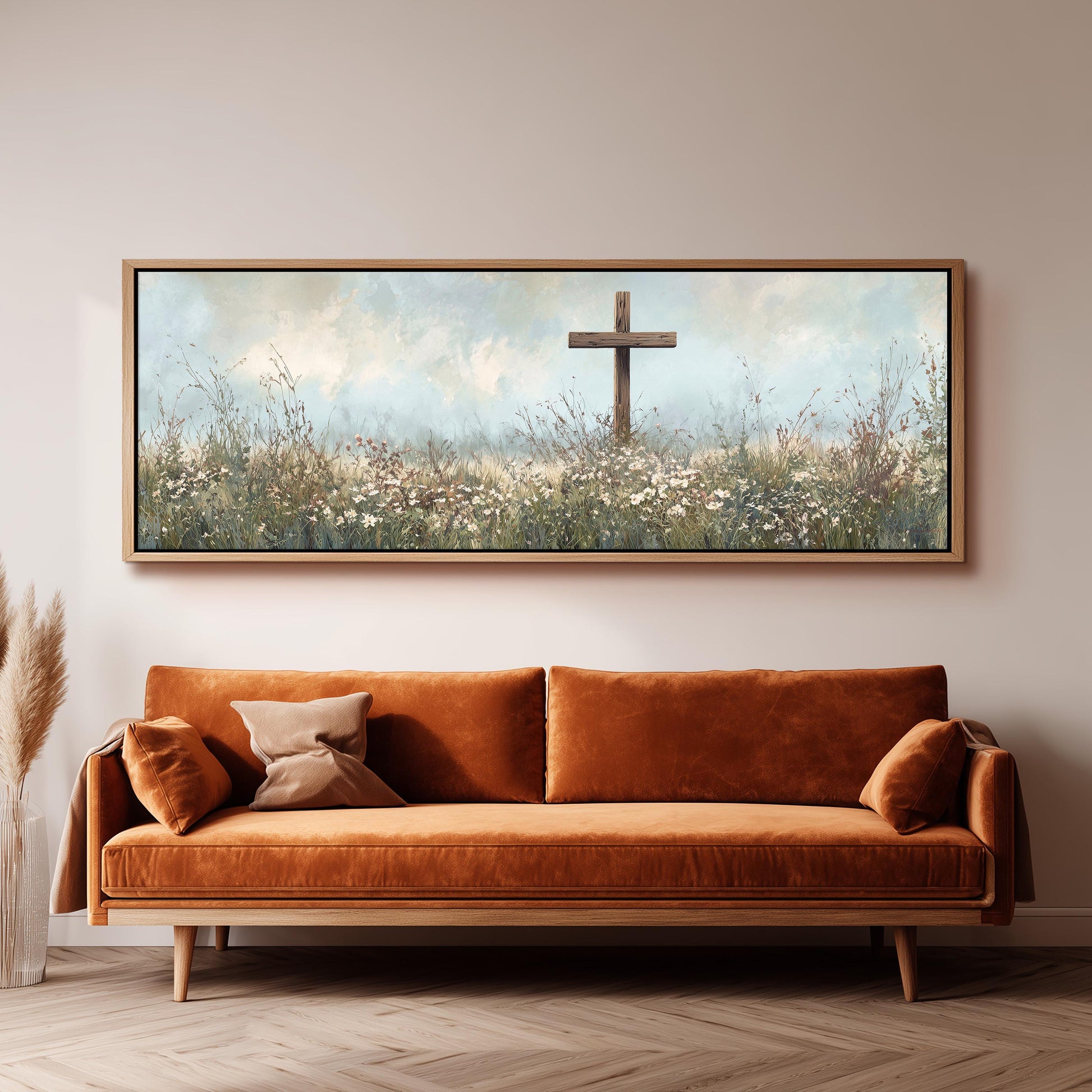 a large painting of a cross in a field of flowers hanging on a wall above a brown sofa.
