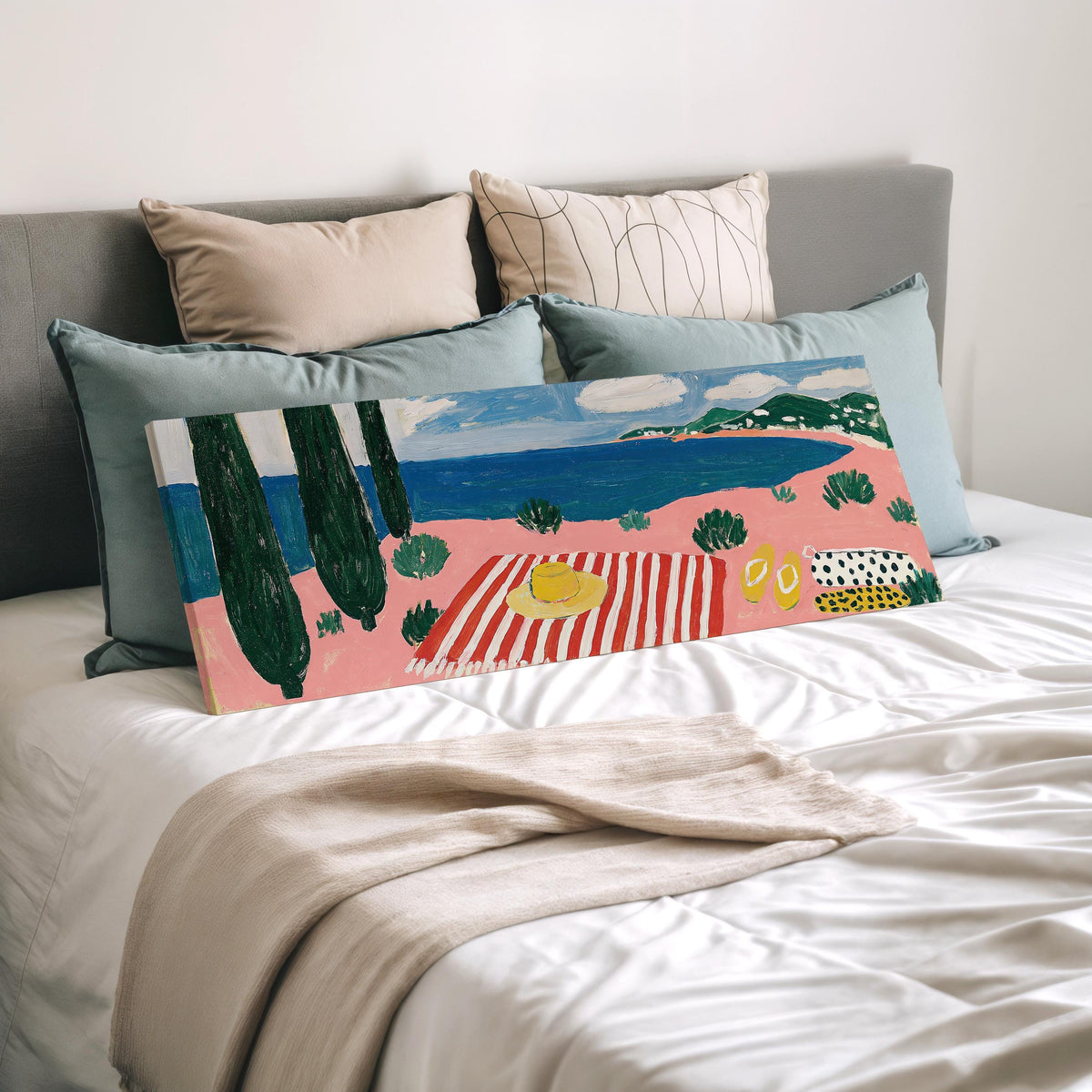 Mediterranean beach day with a striped towel wide panoramic canvas print laid on a bed to show its size
