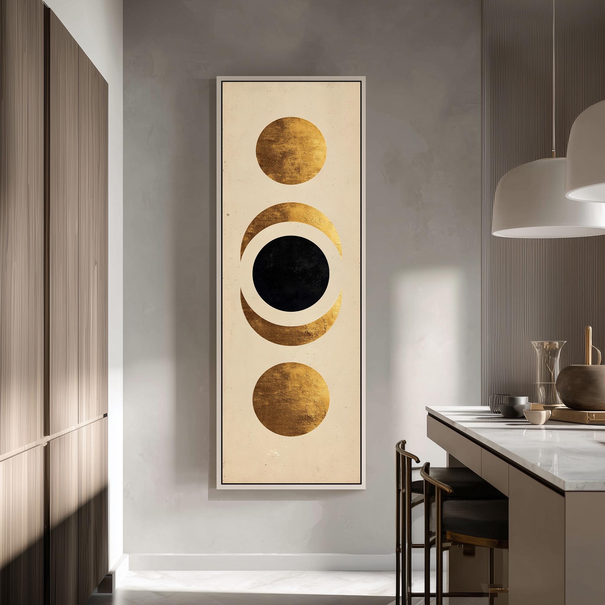 a modern kitchen with a large abstract painting hanging on the wall. The painting consists of three circles, each with a different color: gold, black, and white. The kitchen is well-lit, with a countertop and chairs visible, creating a stylish and contemporary atmosphere.