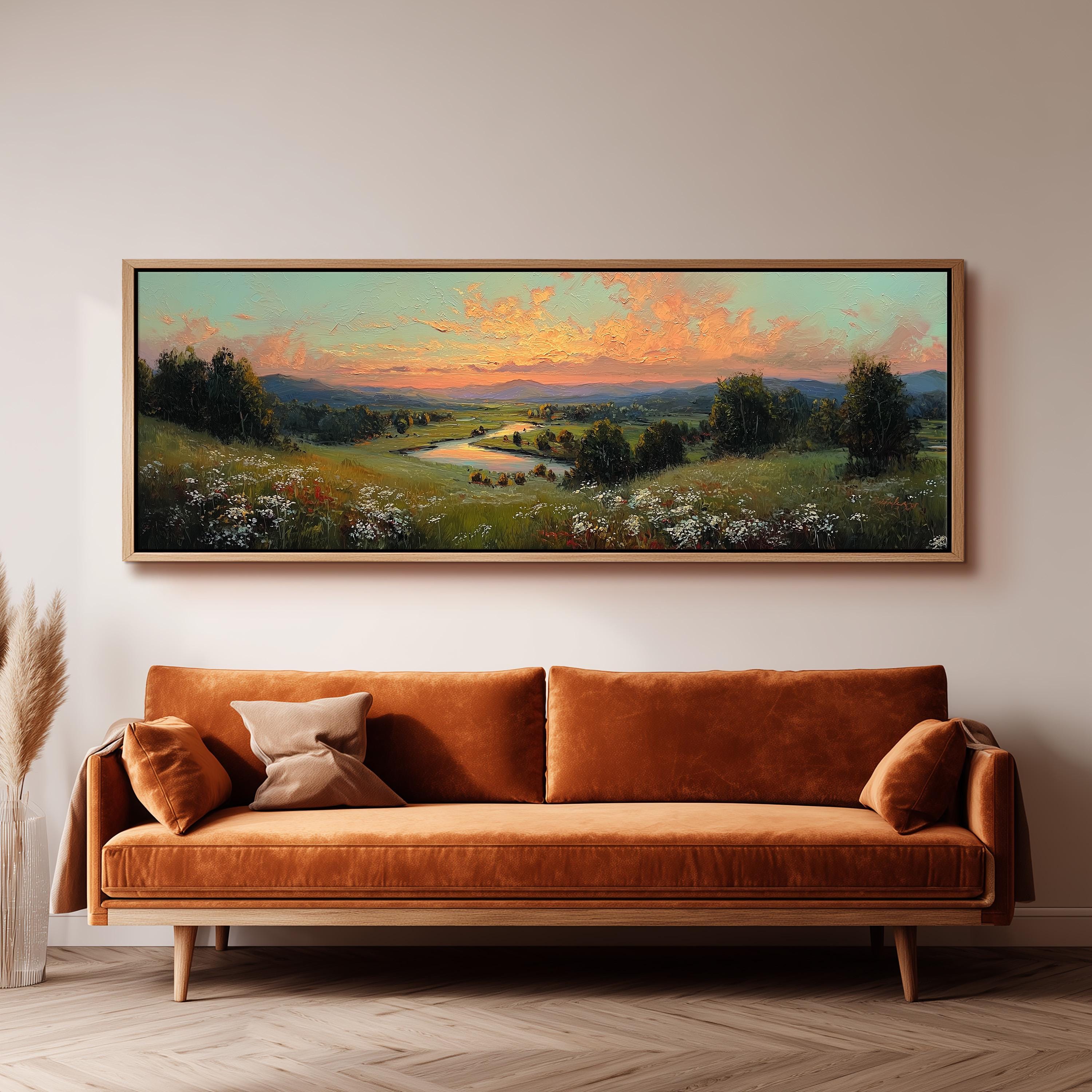 a large landscape painting hanging on a wall above a brown sofa with two pillows.