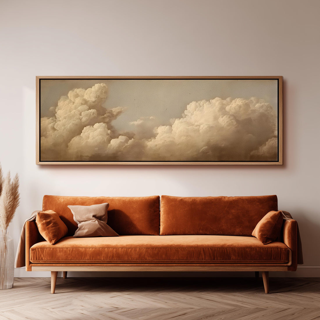 a large, framed painting of a cloudy sky hanging on a wall above a brown sofa with orange cushions.