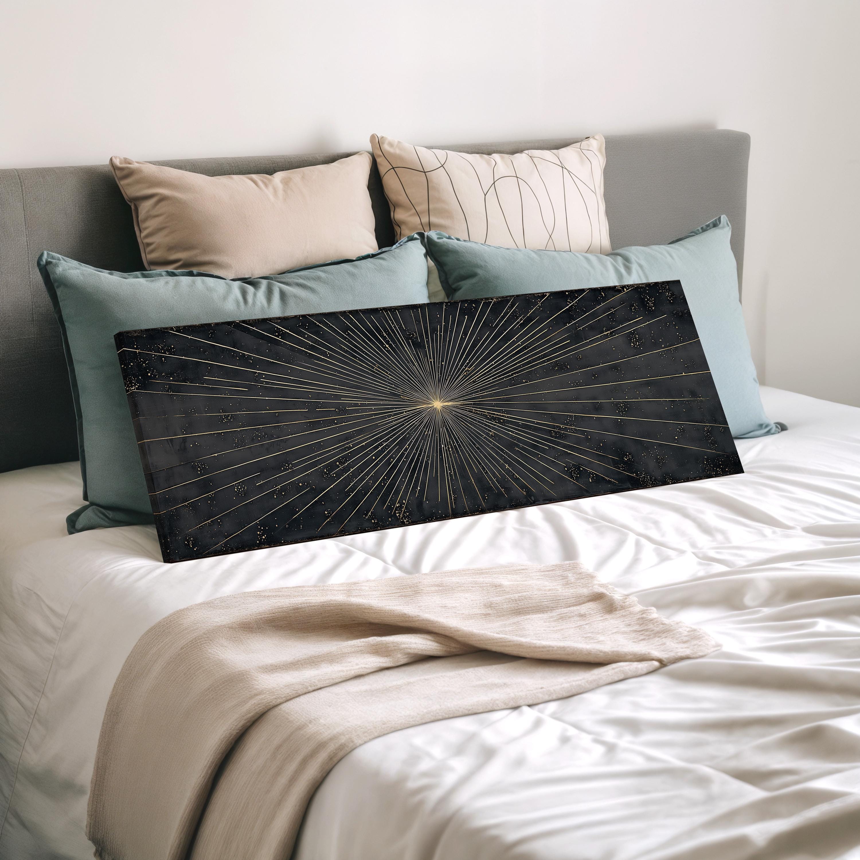 a bed with a black and gold starburst design on the white comforter, surrounded by various pillows in different colors.