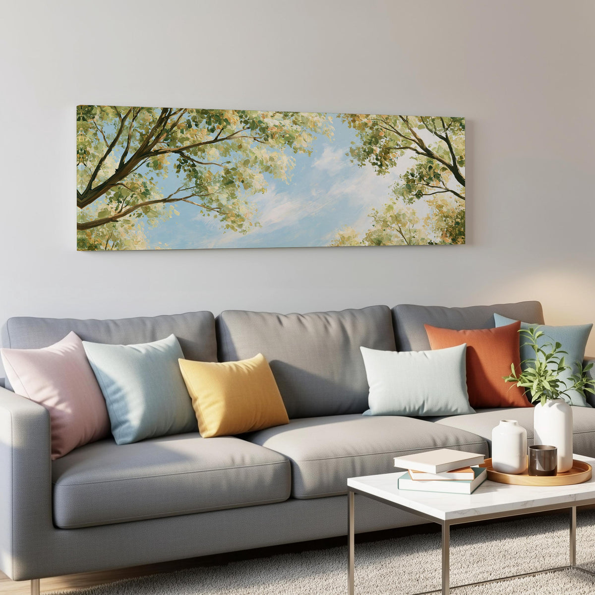 Sunlit leafy branches framing soft clouds panoramic canvas print above a grey sofa in a living room