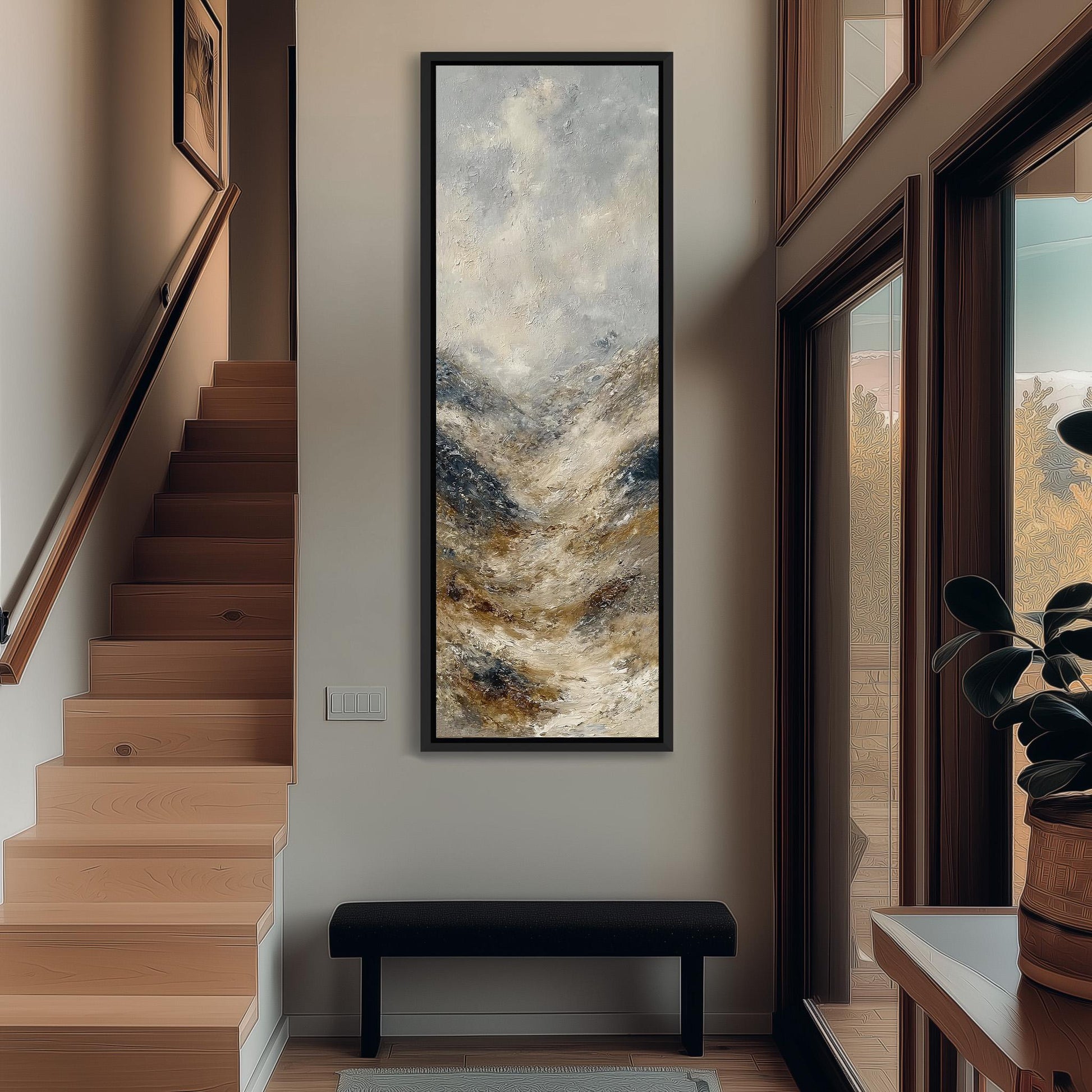 a modern interior design with a large painting hanging on the wall above a black bench. The painting depicts a landscape with mountains and a cloudy sky, creating a serene and calming atmosphere. The room is well-lit, with natural light coming in through the windows, and the wooden staircase adds a touch of warmth and elegance to the space.