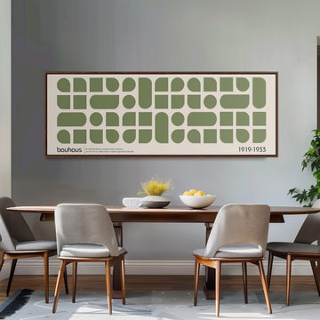 a dining room with a wooden table and four chairs, a large framed poster on the wall above the table, and a bowl of fruit on the table.